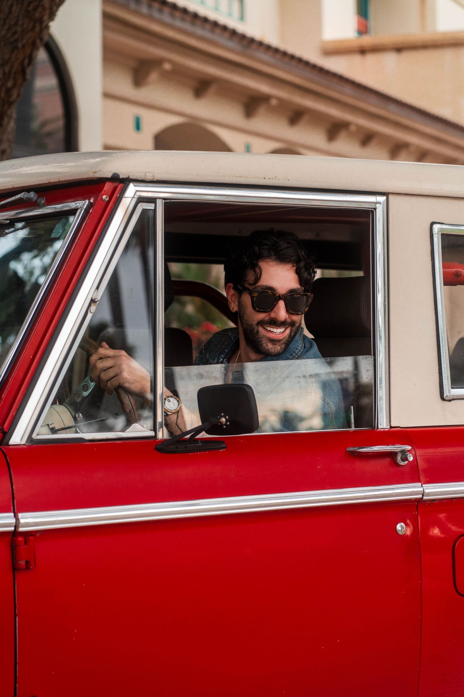 Classic lifestyle photography in Boca Raton, FL – man in sunglasses driving a red vintage Bronco, capturing retro vibes.