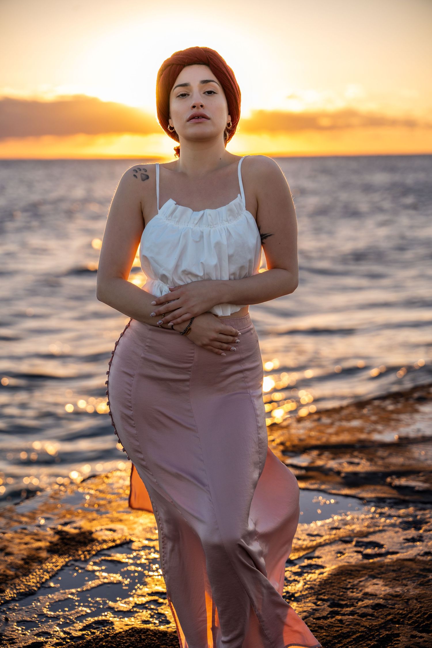 Dramatic seascape portrait by the water in Miami – a woman gazes at the horizon as waves crash behind her, bathed in golden light.