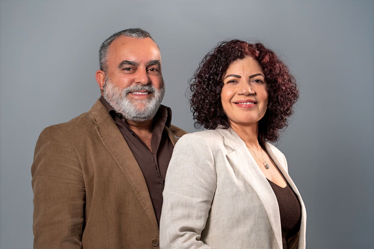 Professional couple posing together against gray studio backdrop