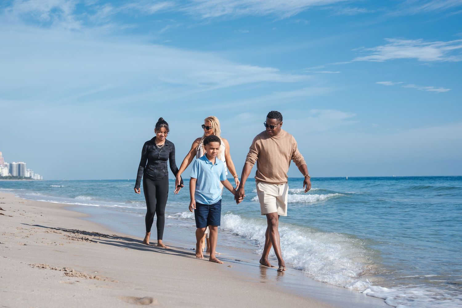 Family walking along the shoreline during a Thanksgiving beach photo session in South Florida.