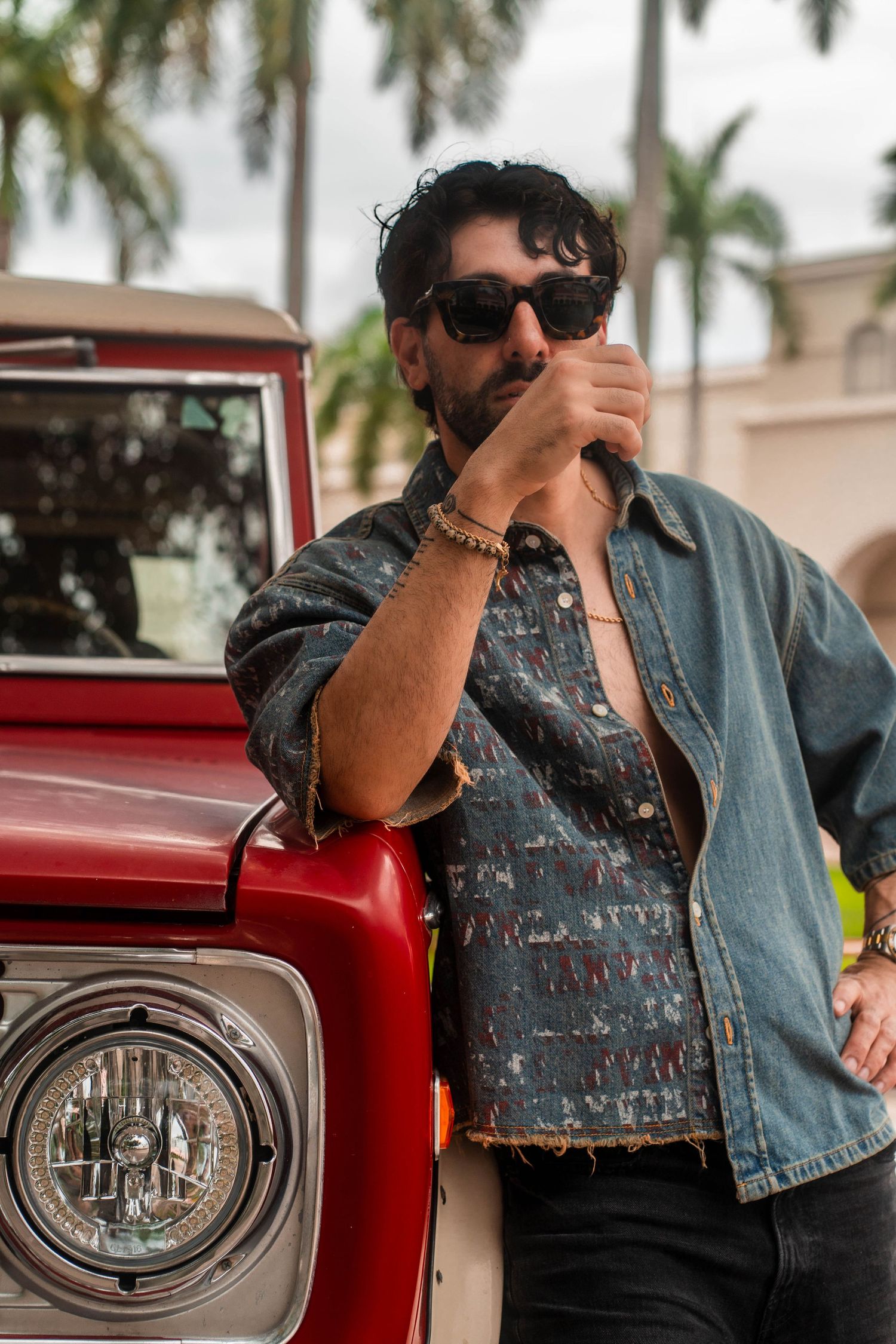 Vintage-inspired lifestyle portrait in Boca Raton, FL – man in sunglasses leans on a classic red Ford Bronco, exuding retro charm.