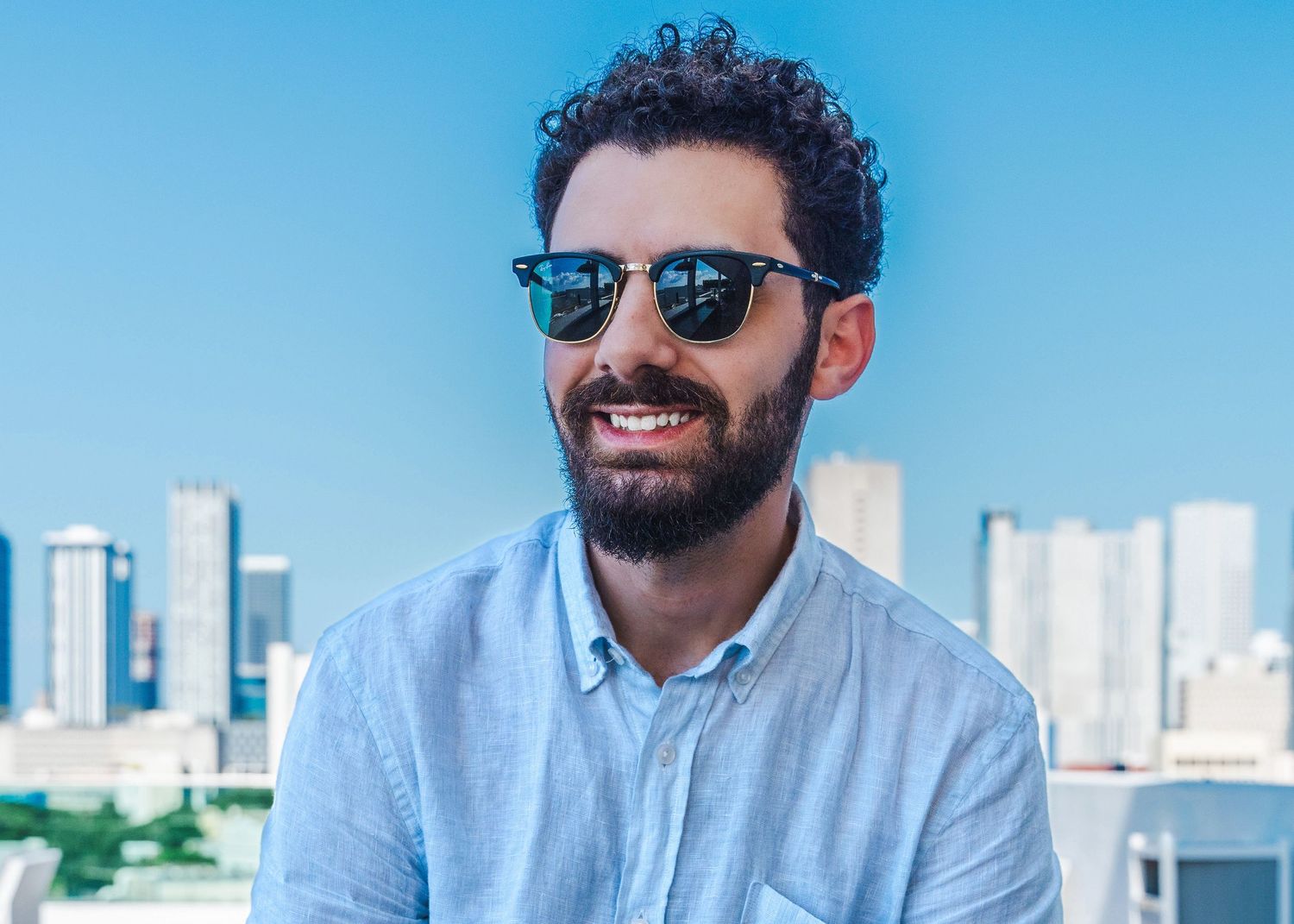 Man wearing sunglasses during rooftop portrait session in Miami skyline setting