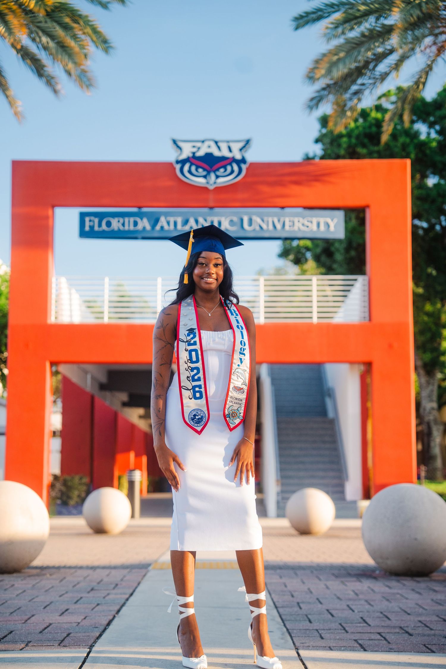 Full body FAU graduation portrait created through a guided session with graduate in front of iconic Boca Raton campus breezeway