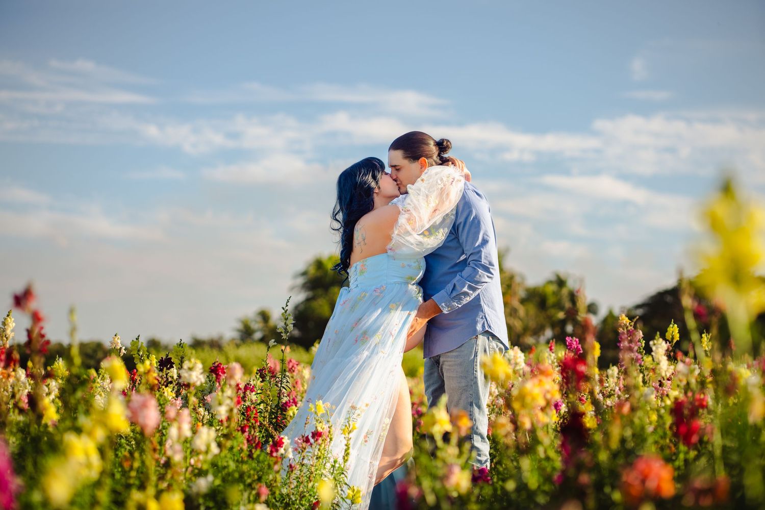 Natural light maternity photo with dad lifting mom in a flower field in Miami.