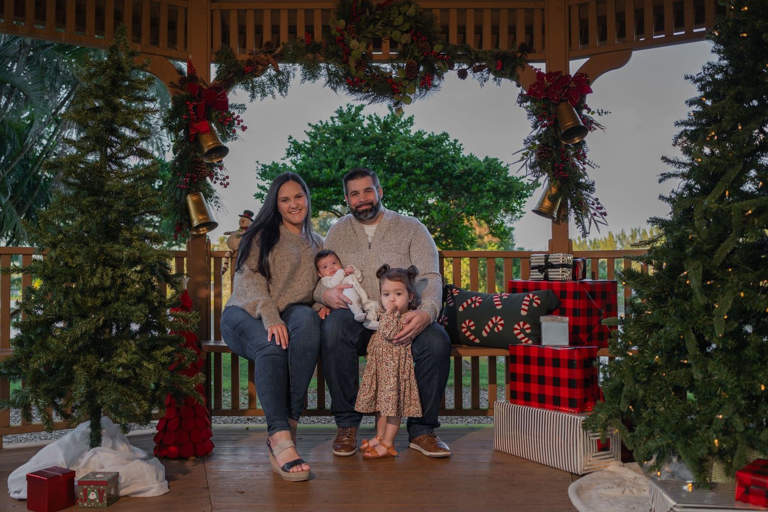Festive holiday family photoshoot in Fort Lauderdale, FL – parents with children enjoying a Christmas-themed setup.