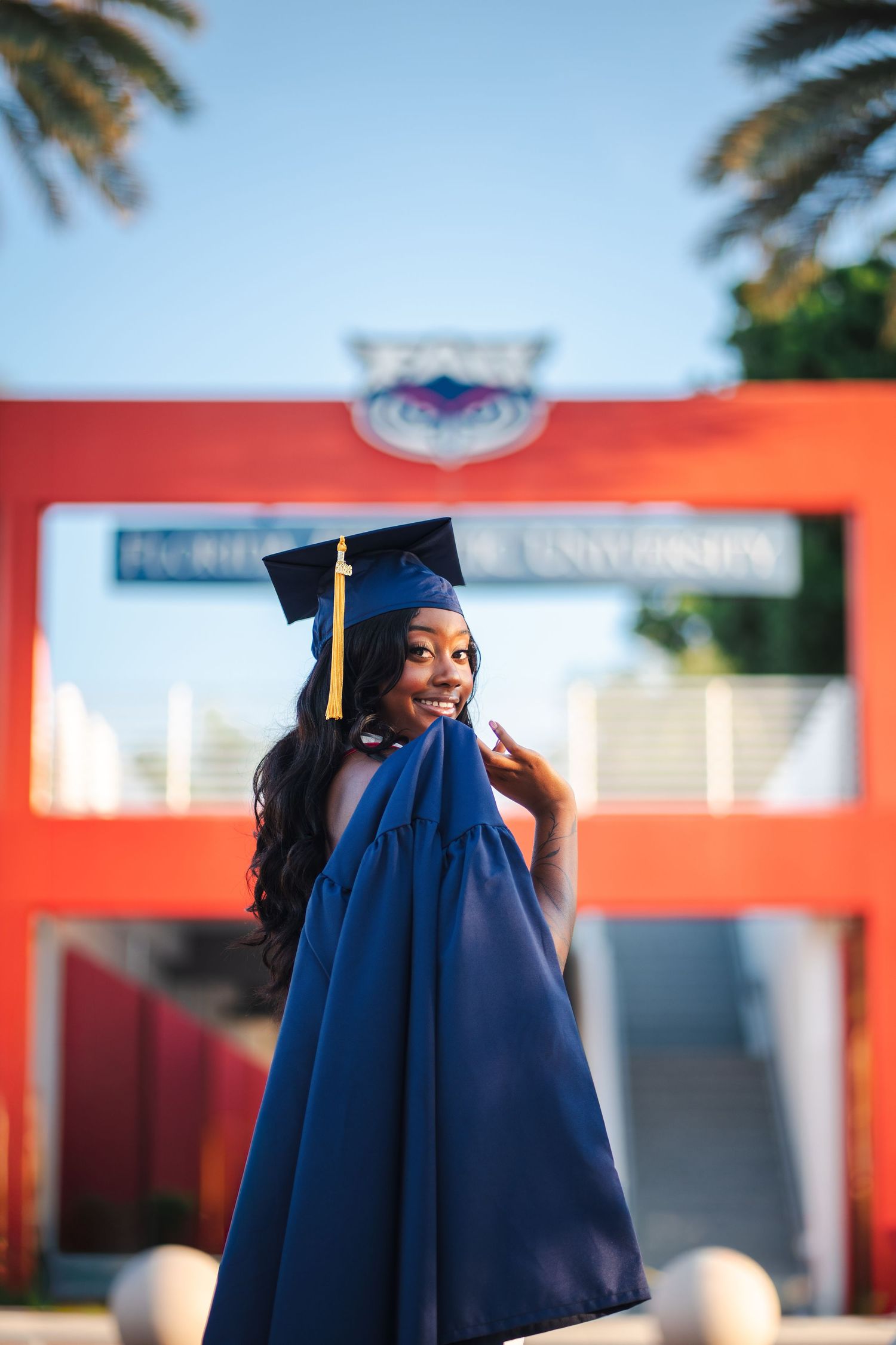Confident FAU graduate captured in a guided portrait experience with cap and gown on Boca Raton campus