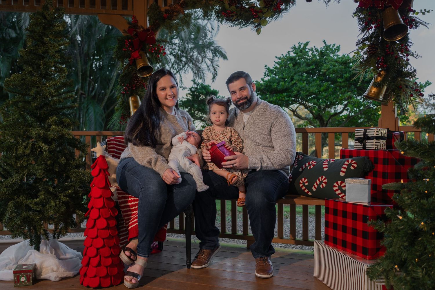 Christmas mini session in Pembroke Pines, FL – joyful baby celebrating the holiday season with parents in a cozy gazebo.