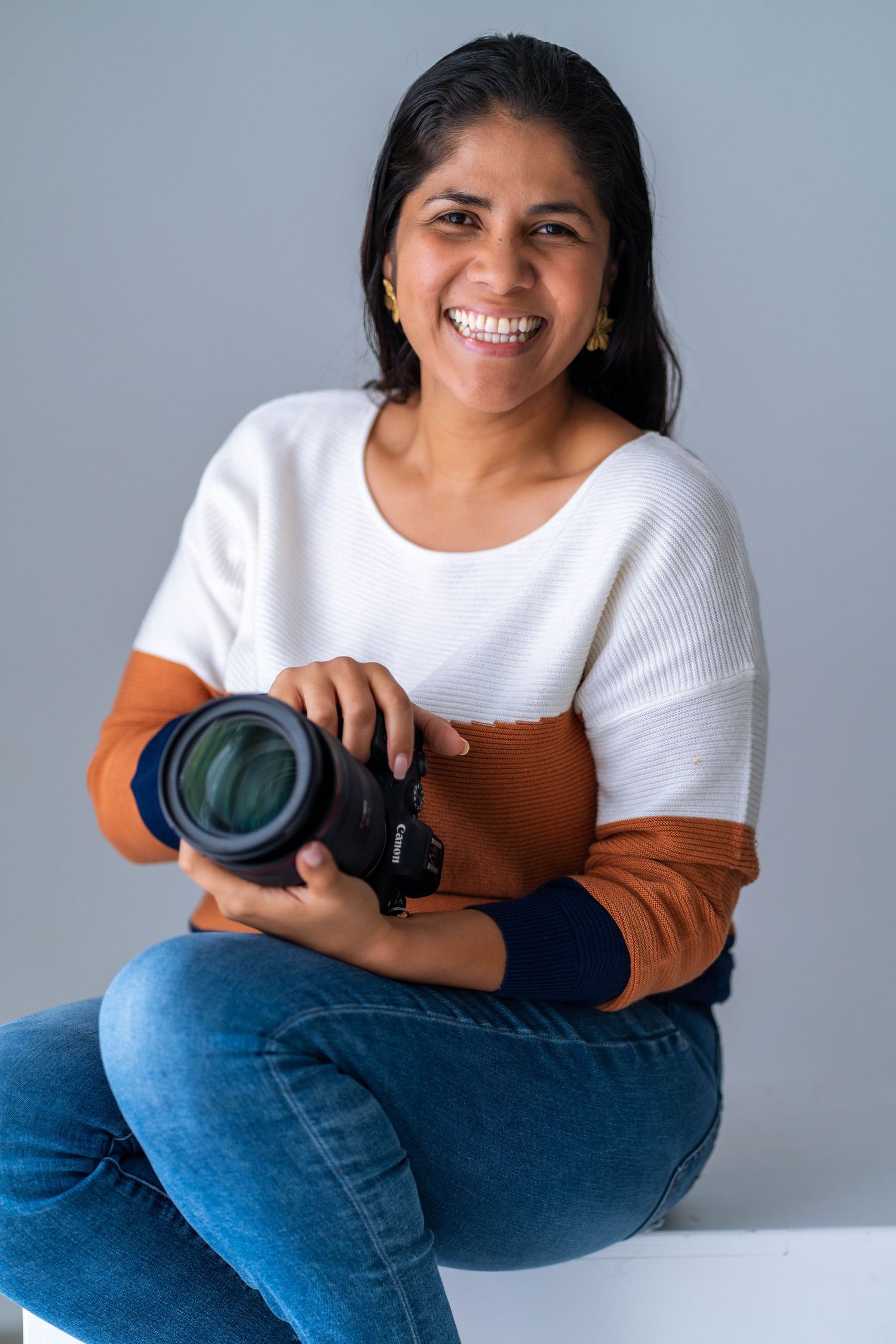 Professional branding session in Miami, FL – smiling female photographer holding a camera in a clean studio setting.