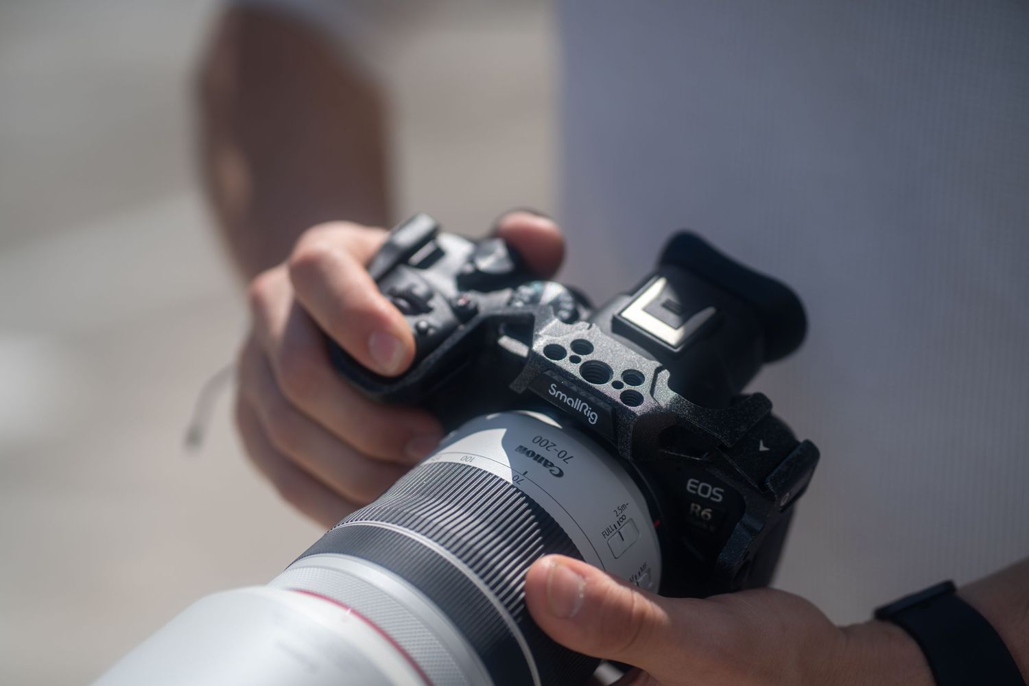 Close-up of hands holding Canon mirrorless camera with telephoto lens, captured during branding shoot in Miami.