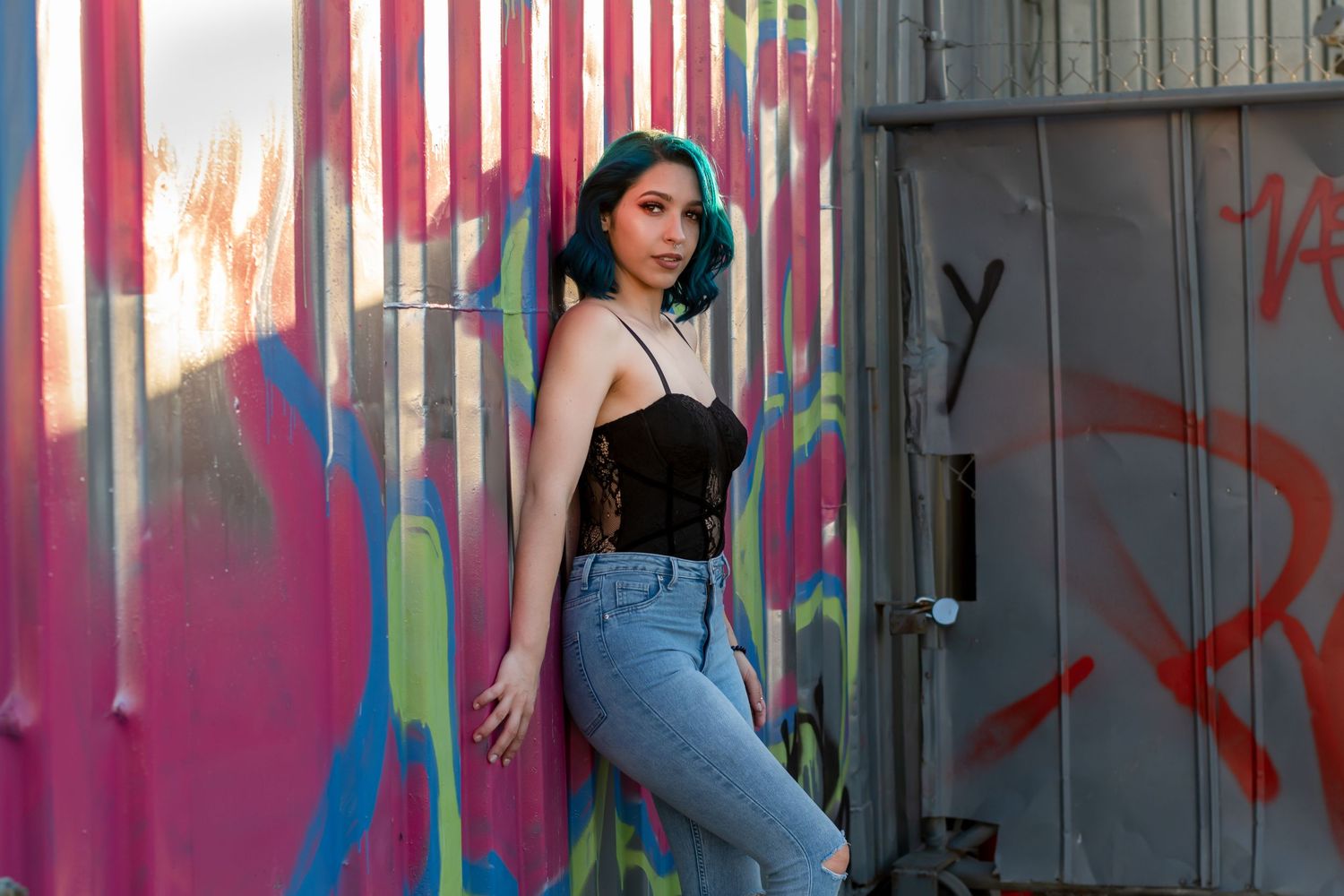 Casual city portrait of a stylish woman in a black lace top and jeans, confidently posing in front of colorful street art. Ft Lauderdale FL