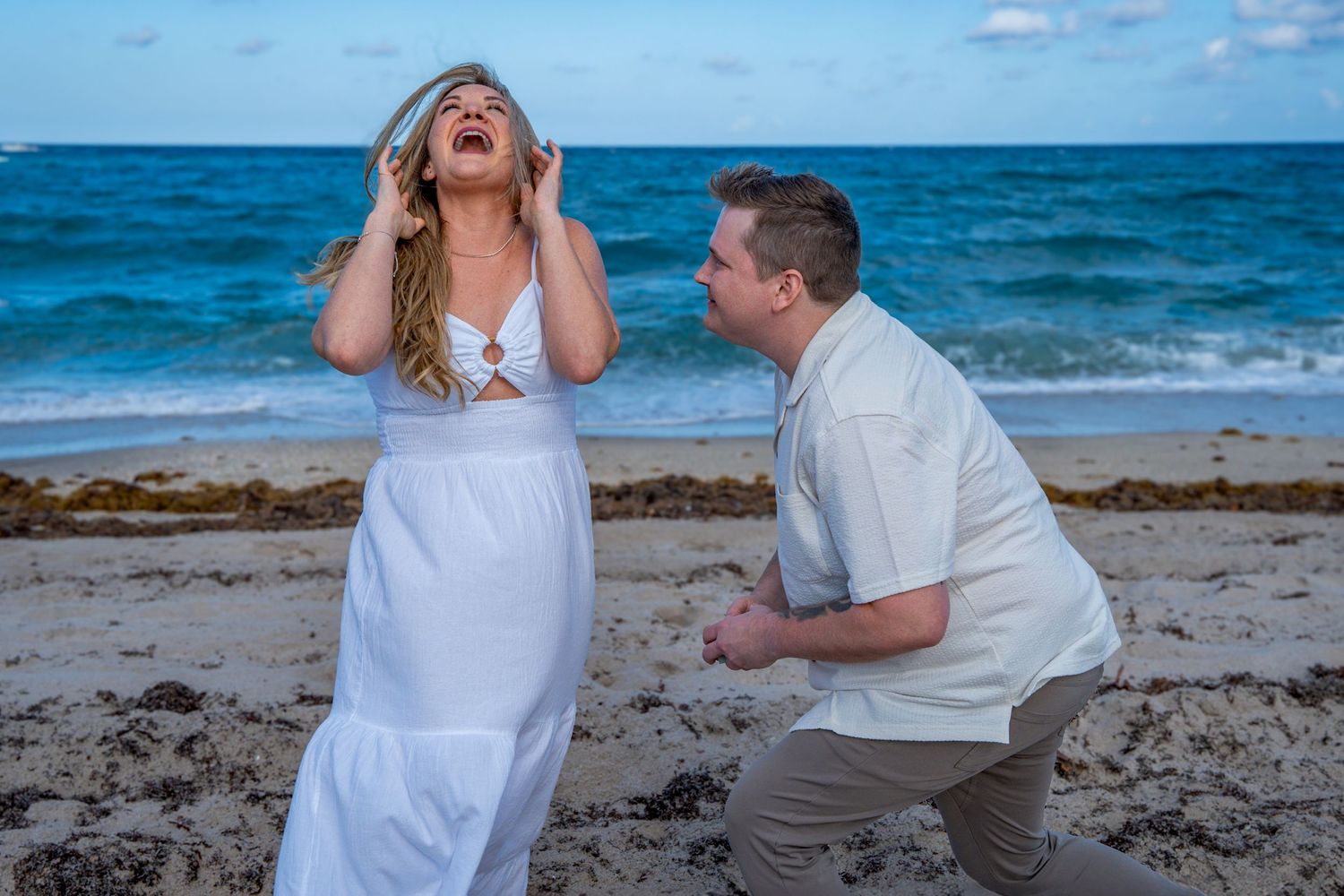 Surprise beach proposal photography capturing the bride-to-be’s emotional reaction to a heartfelt moment.