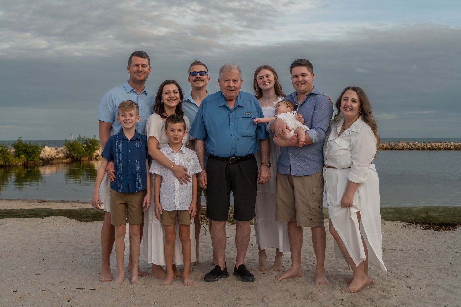 Multi-generational family portrait at Harry Harris Park, Tavernier, FL – smiling together by the beach with a peaceful waterfront view.
