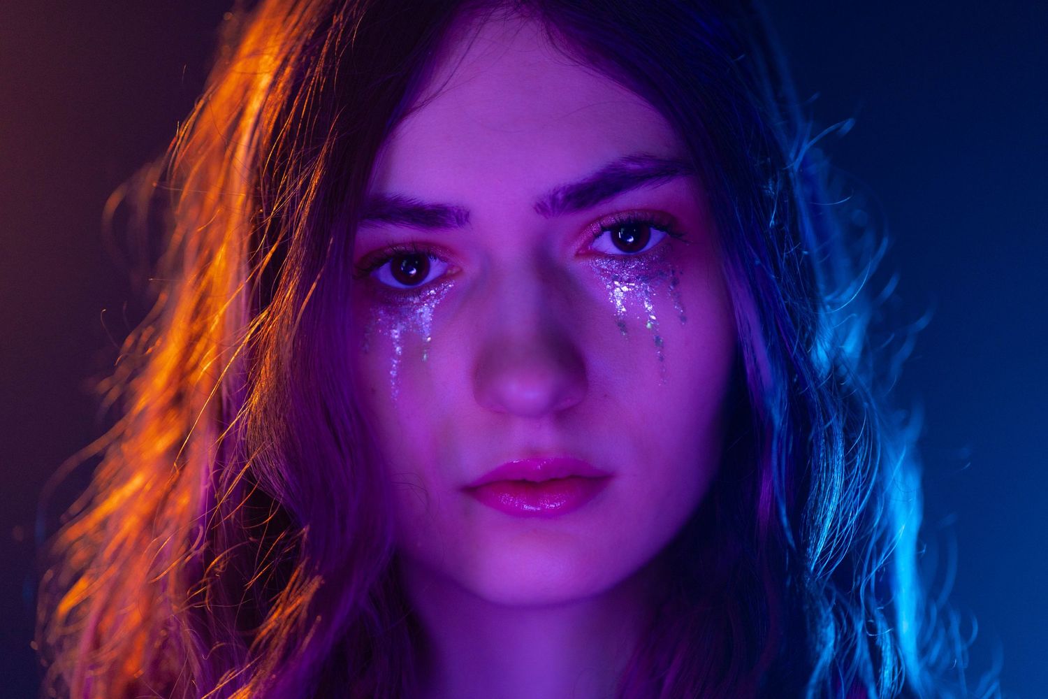 Moody neon portrait in Fort Lauderdale, FL – woman with artistic lighting and tears of glitter for a cinematic effect.