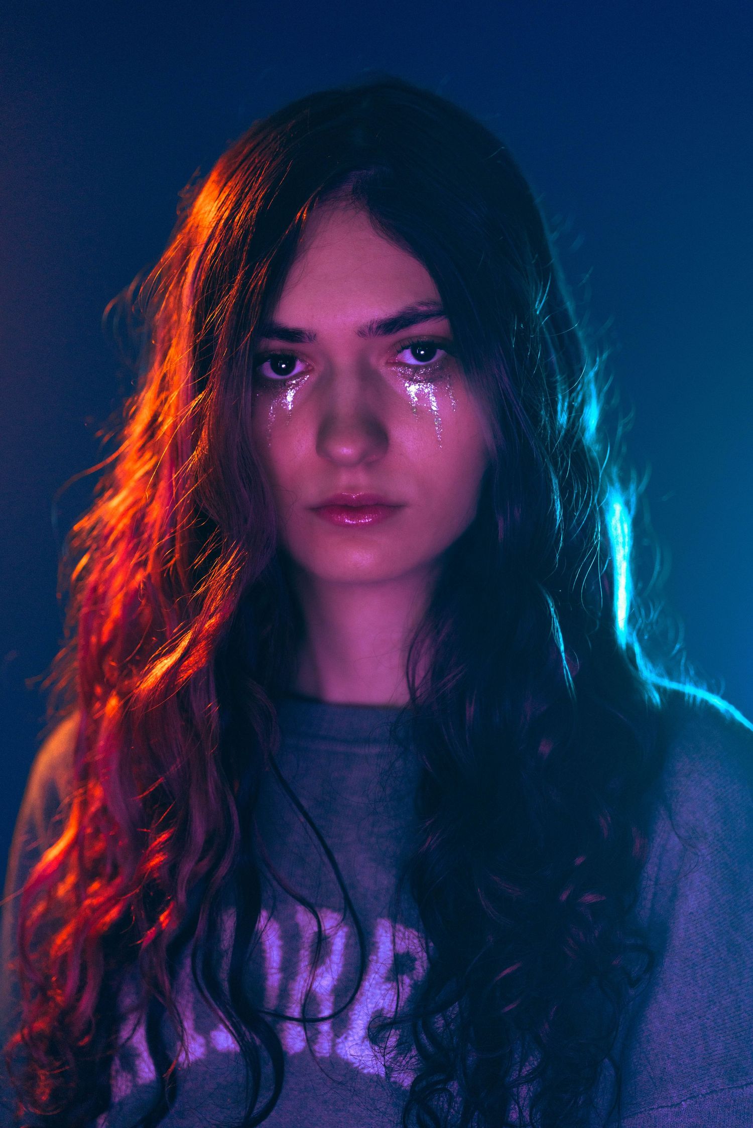 Artistic moody portrait in Fort Lauderdale, FL – woman in soft blue and pink neon hues with an intense gaze.