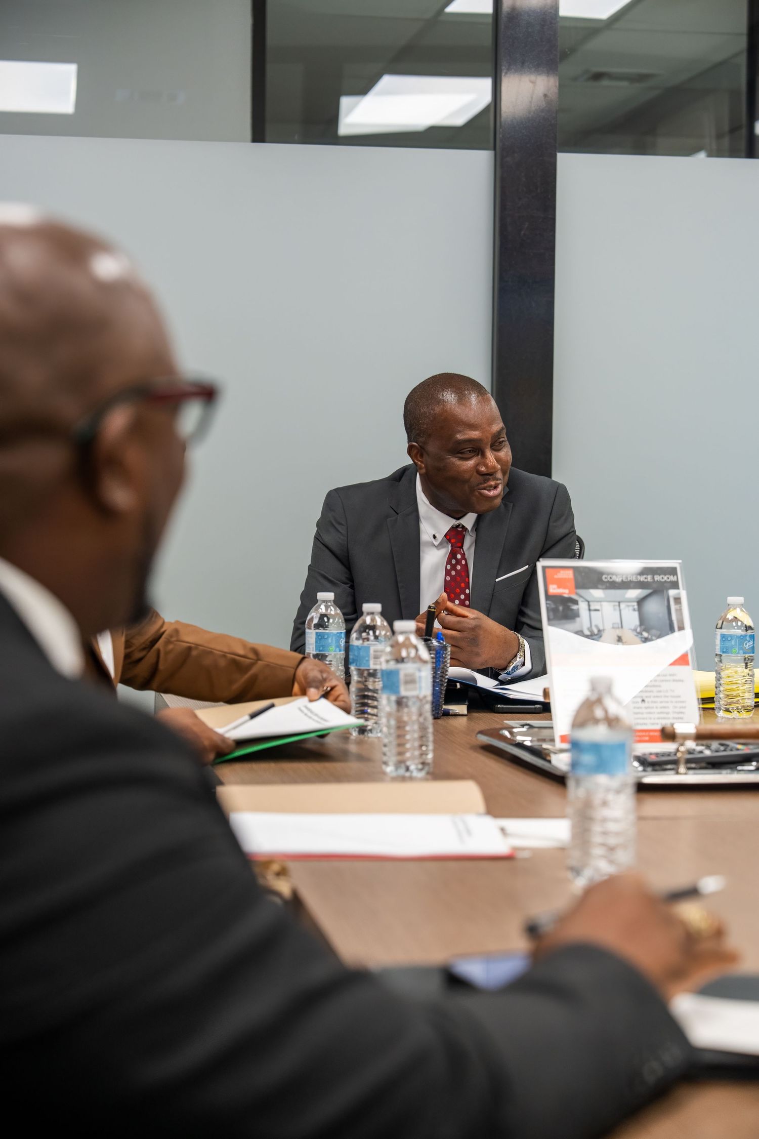 Business meeting candid of executives in discussion around a conference table inside a corporate office.