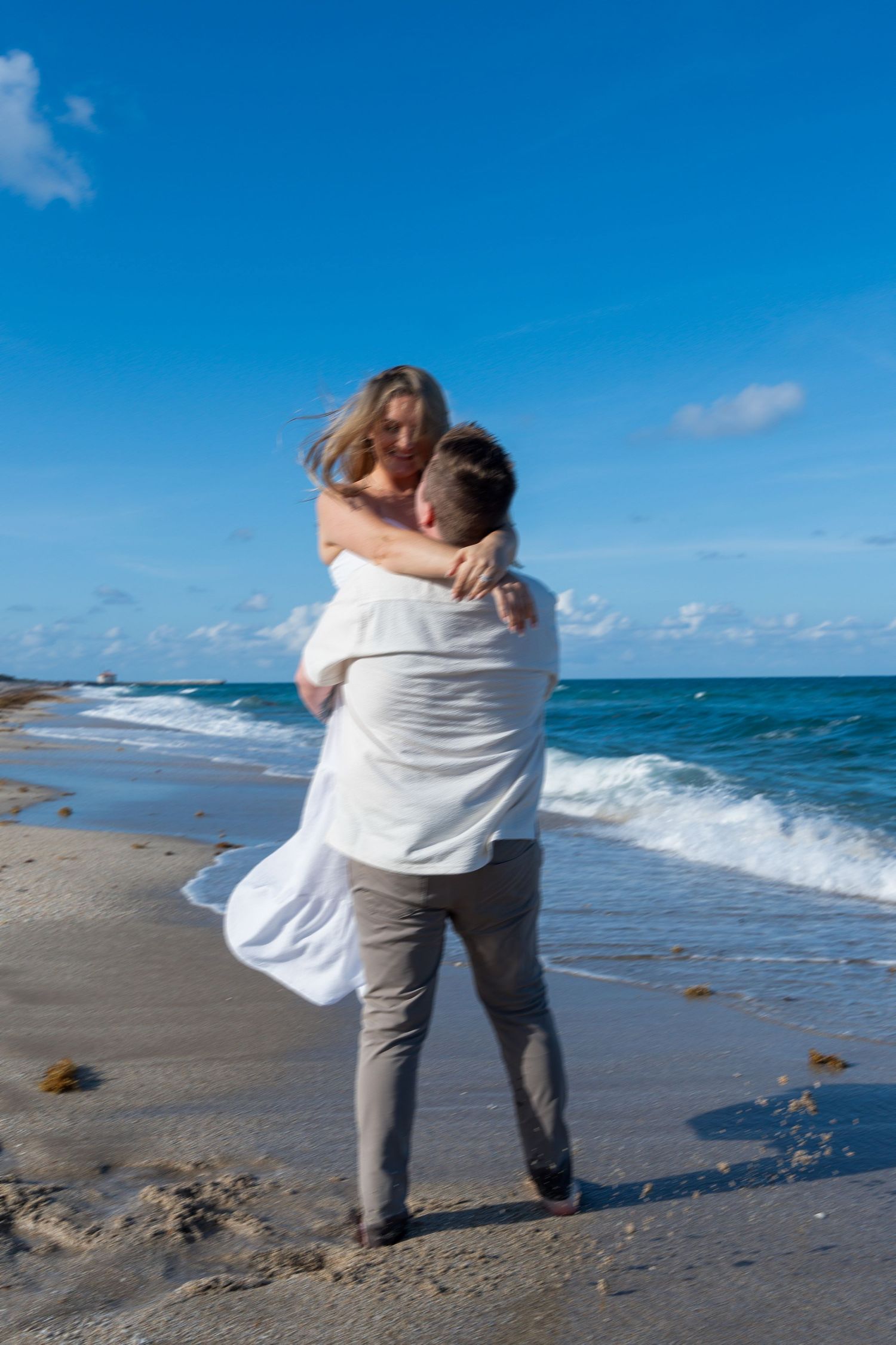 Candid beach engagement session capturing pure joy as the newly engaged couple celebrates by the water