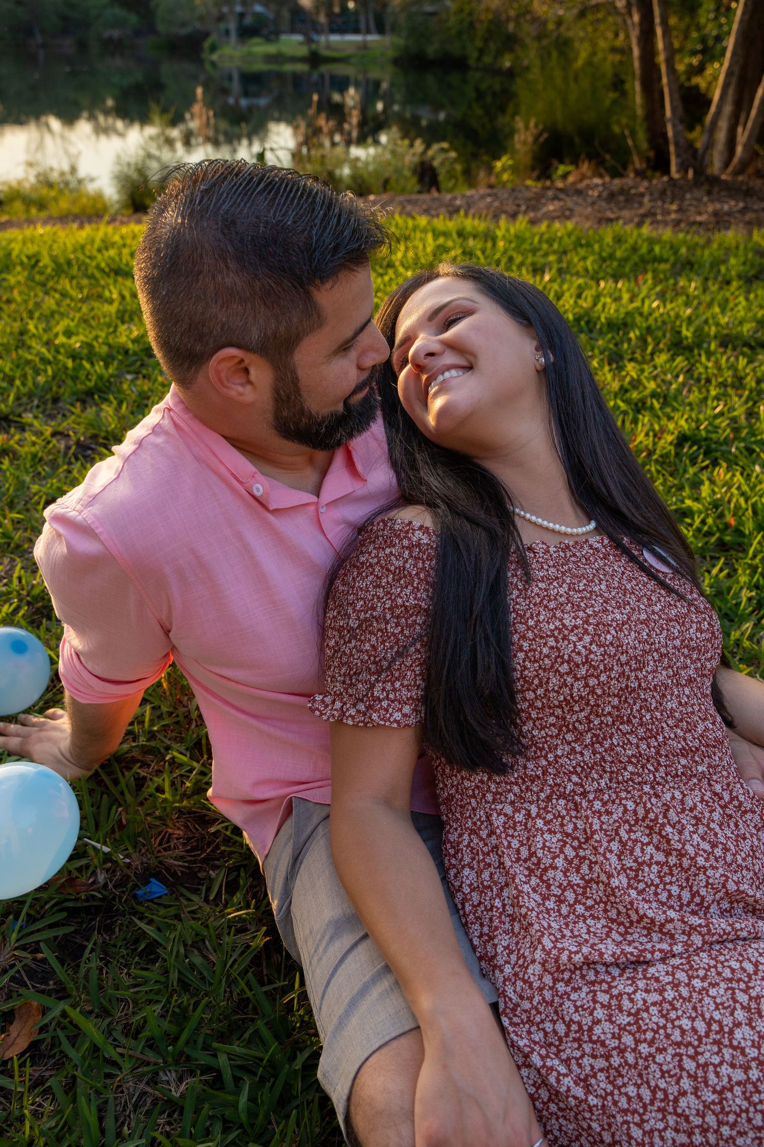 Couple sharing a candid moment on the grass during a South Florida maternity photo session.