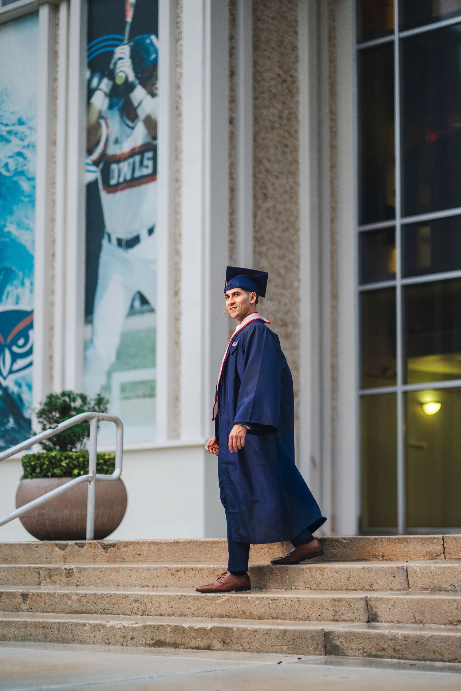 FAU graduation photo of a graduate walking up campus steps in cap and gown at Florida Atlantic University.