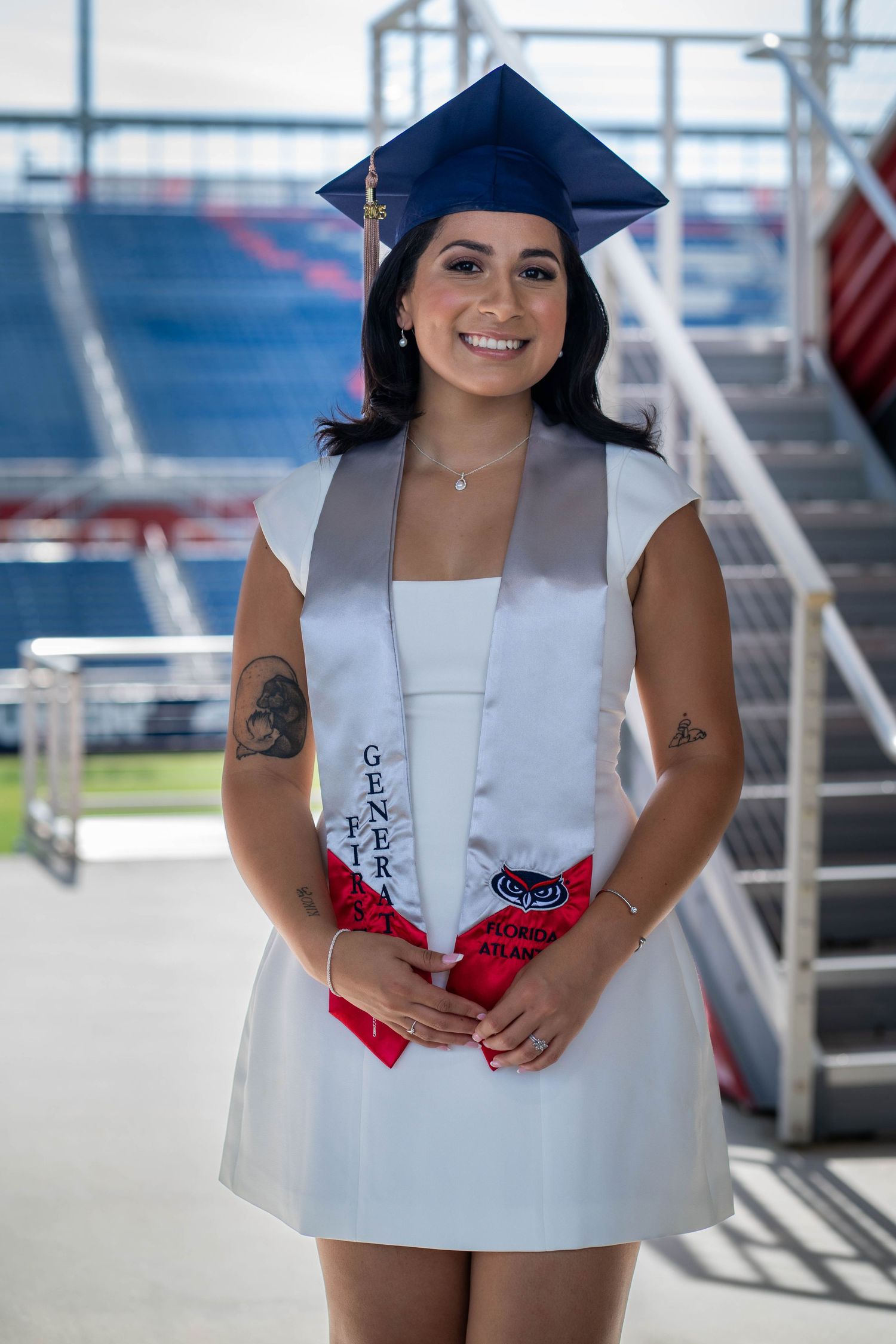 FAU graduate seated in stadium bleachers before graduation photography session