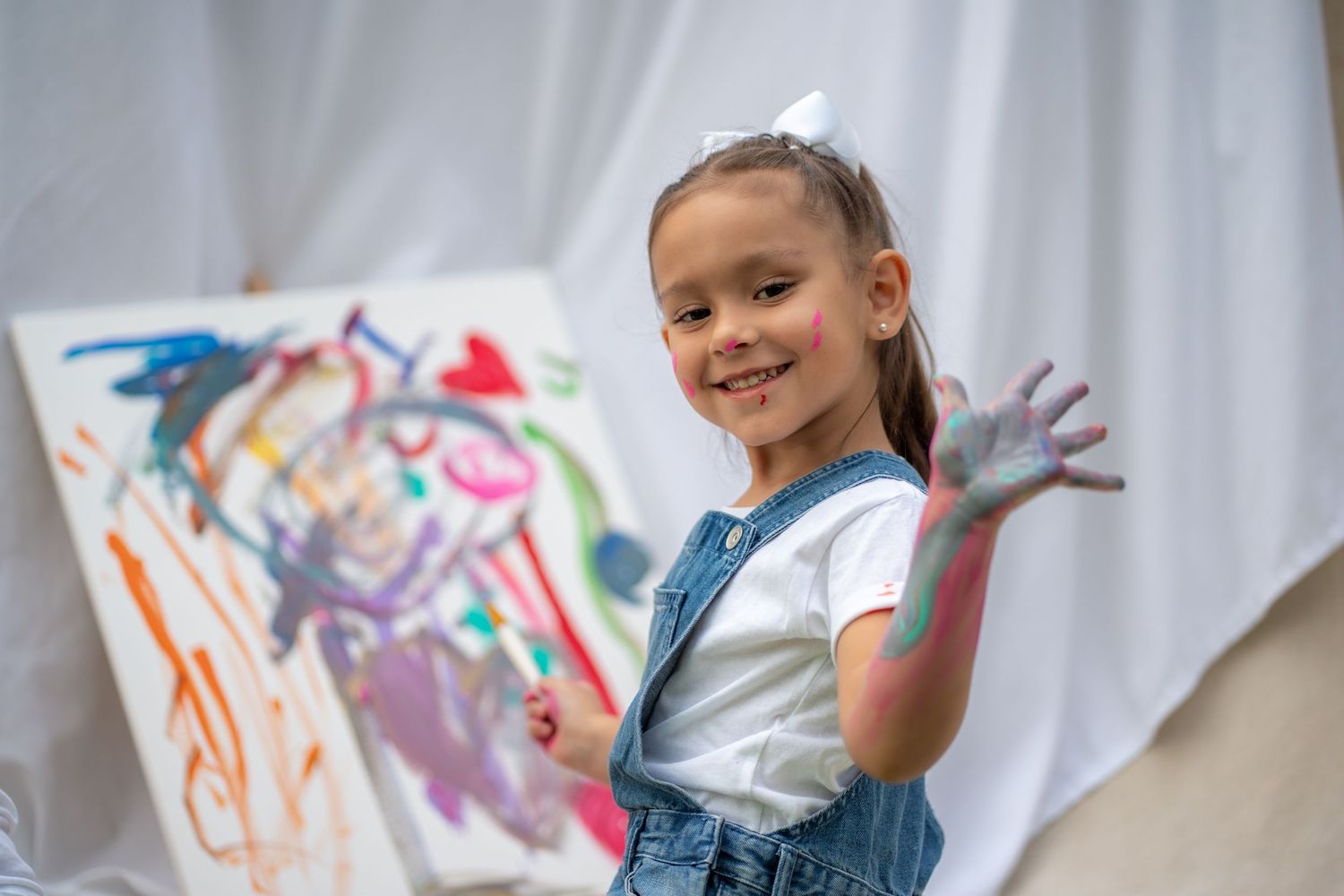 Little girl smiling and showing off her colorful hand during a playful outdoor session in Pembroke Pines.
