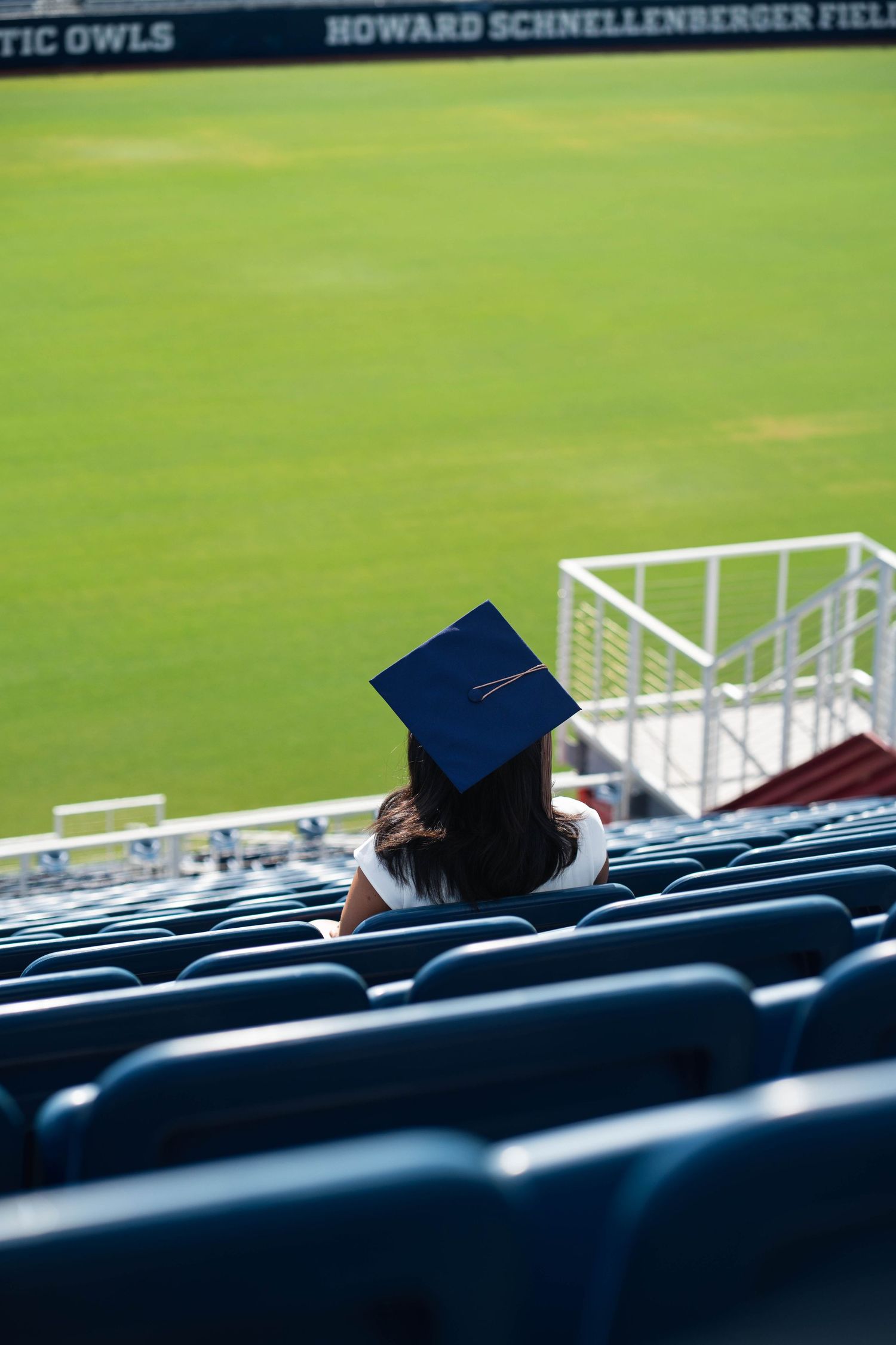 FAU graduate seated in stadium bleachers before graduation photography session