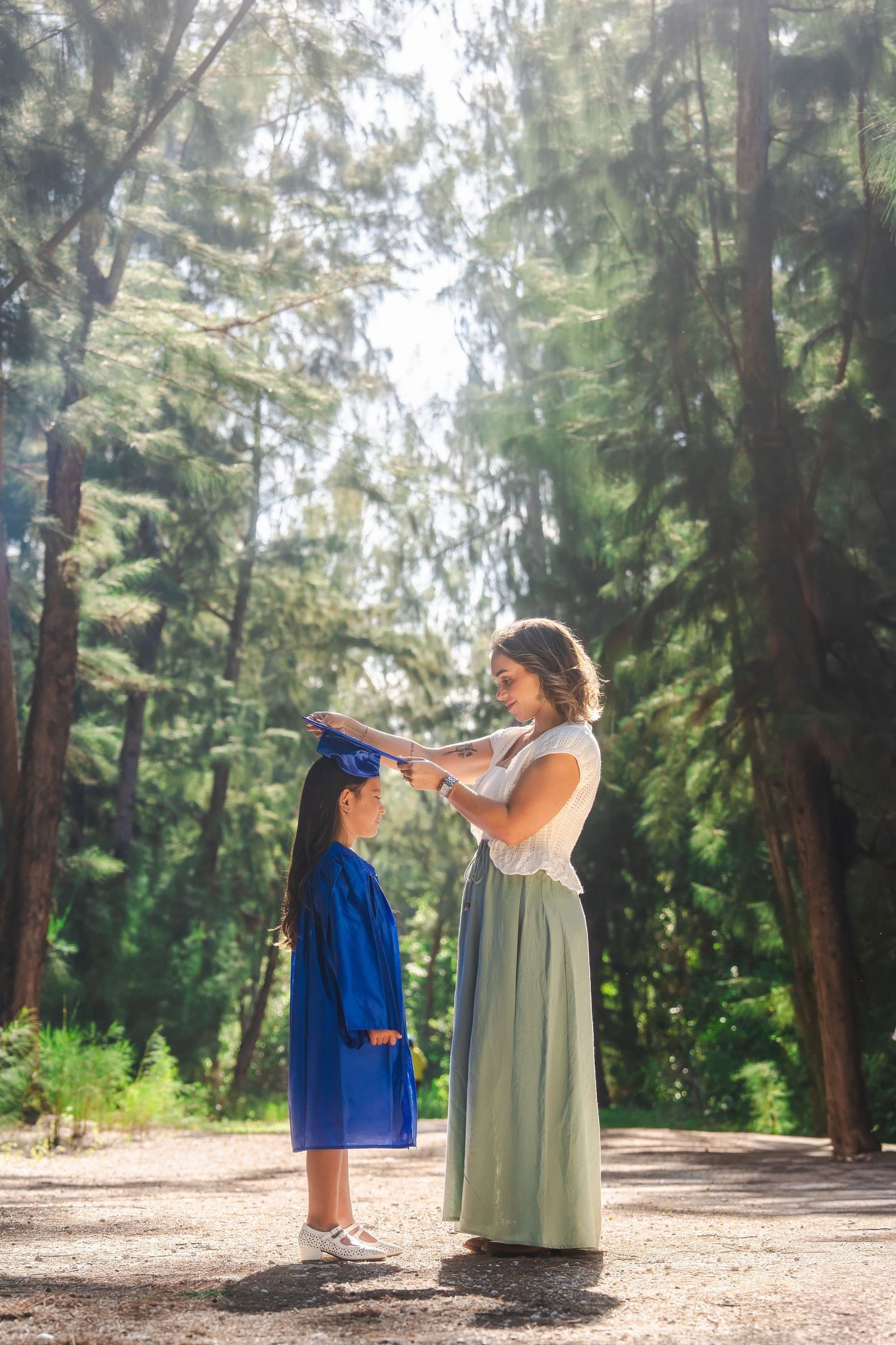 Kindergarten graduation session at Tree Tops Park in Davie by South Florida photographer, mom adjusting daughter’s cap