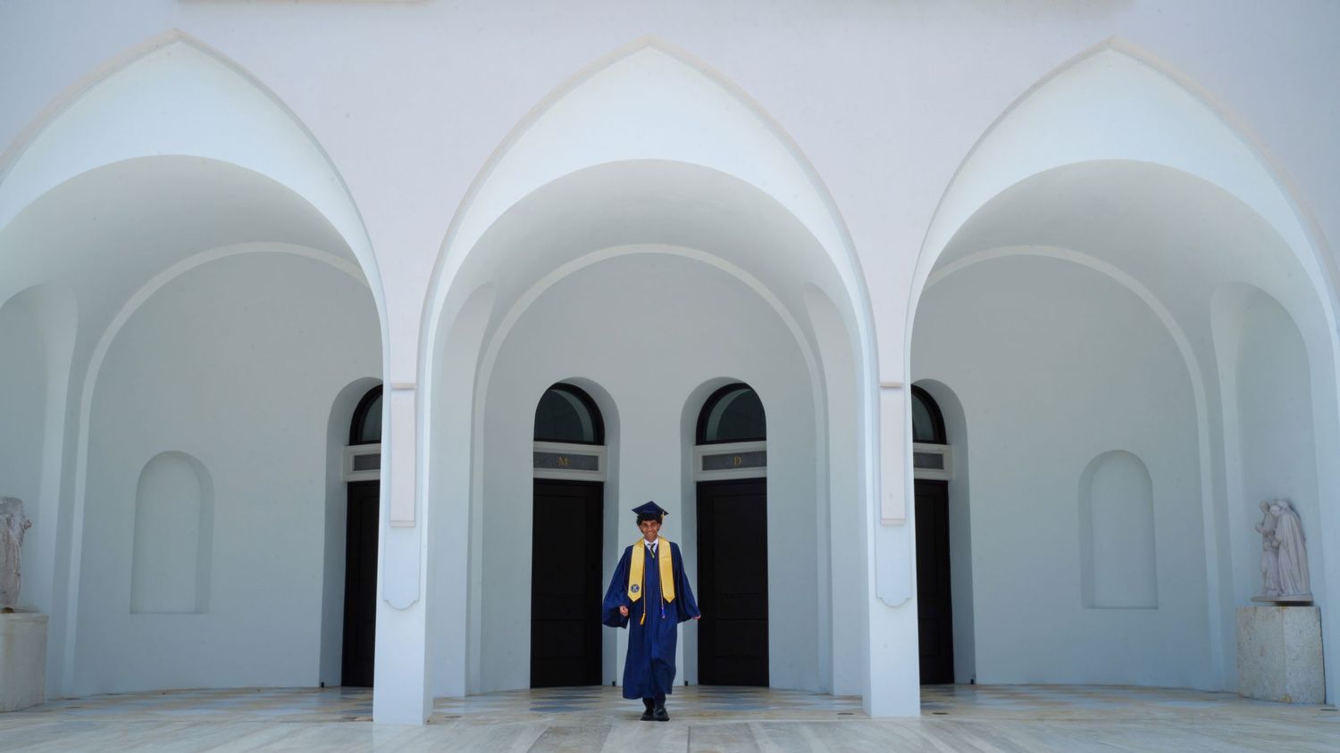 Senior graduation portrait in front of Berlin High School’s elegant white arches, wearing a blue cap and gold stole. Miami senior photograph