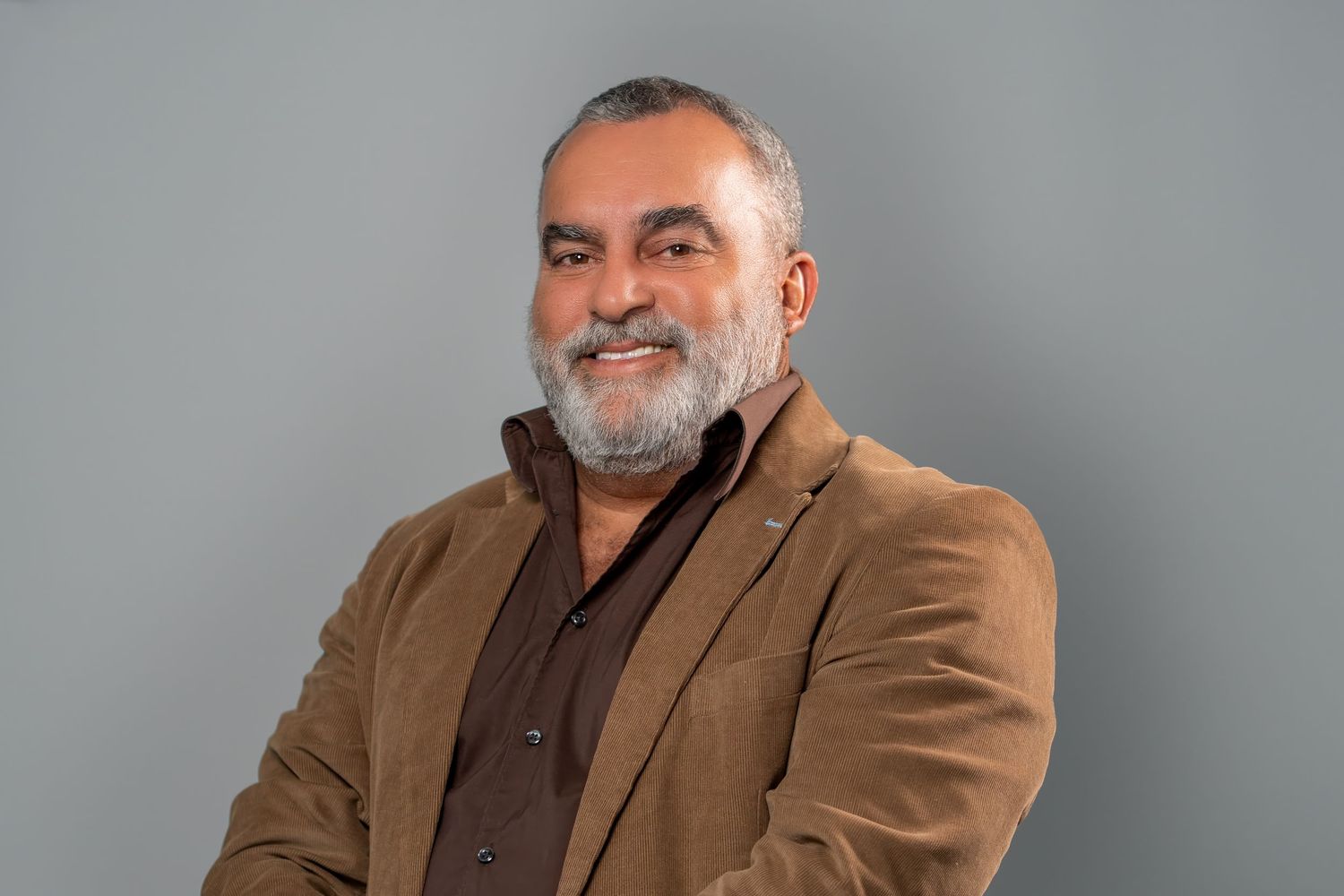 Man in brown blazer posing for studio professional headshot