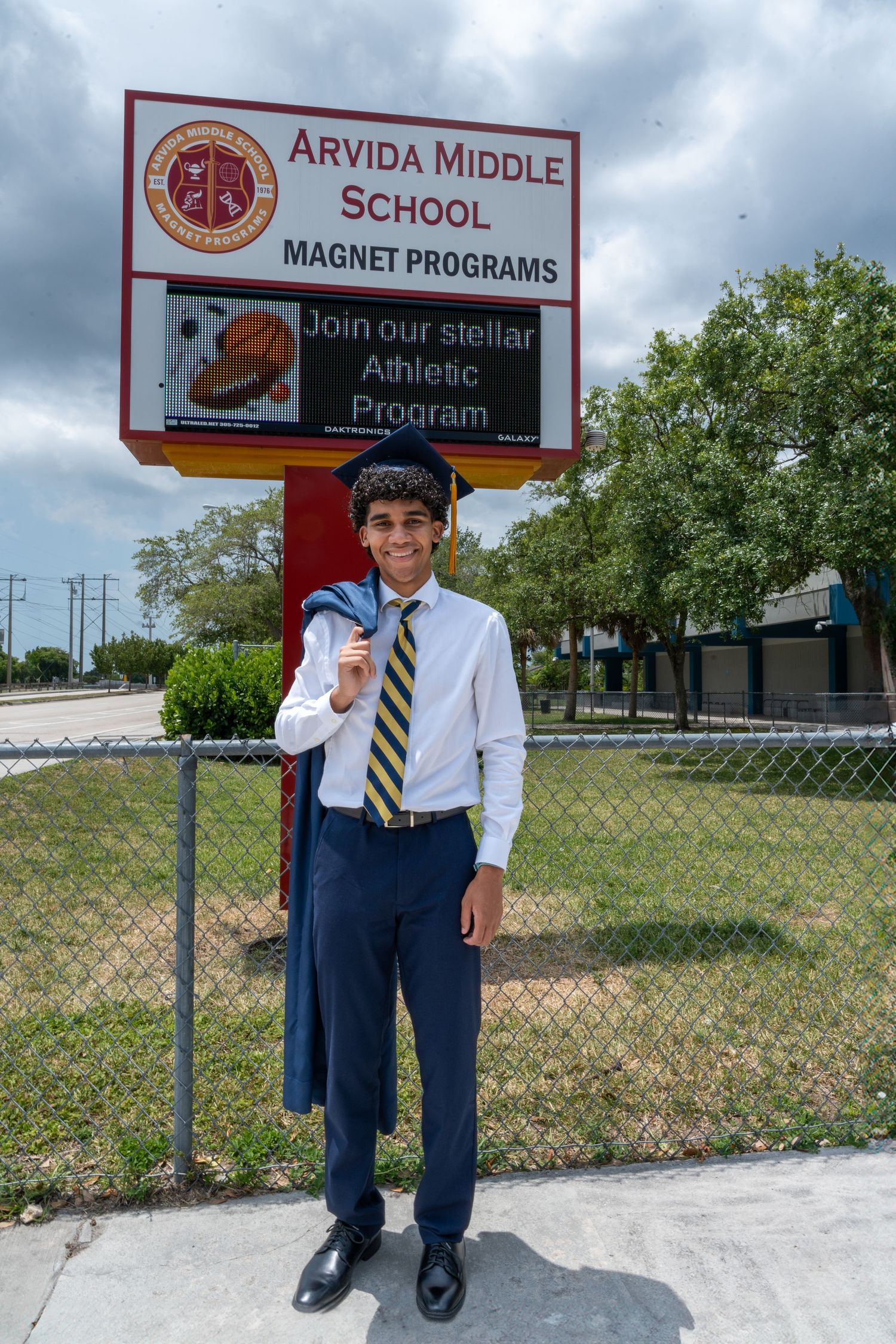 Senior boy poses proudly at Arvida Middle School in formal attire, capturing his journey from middle school to high school graduation in Sou