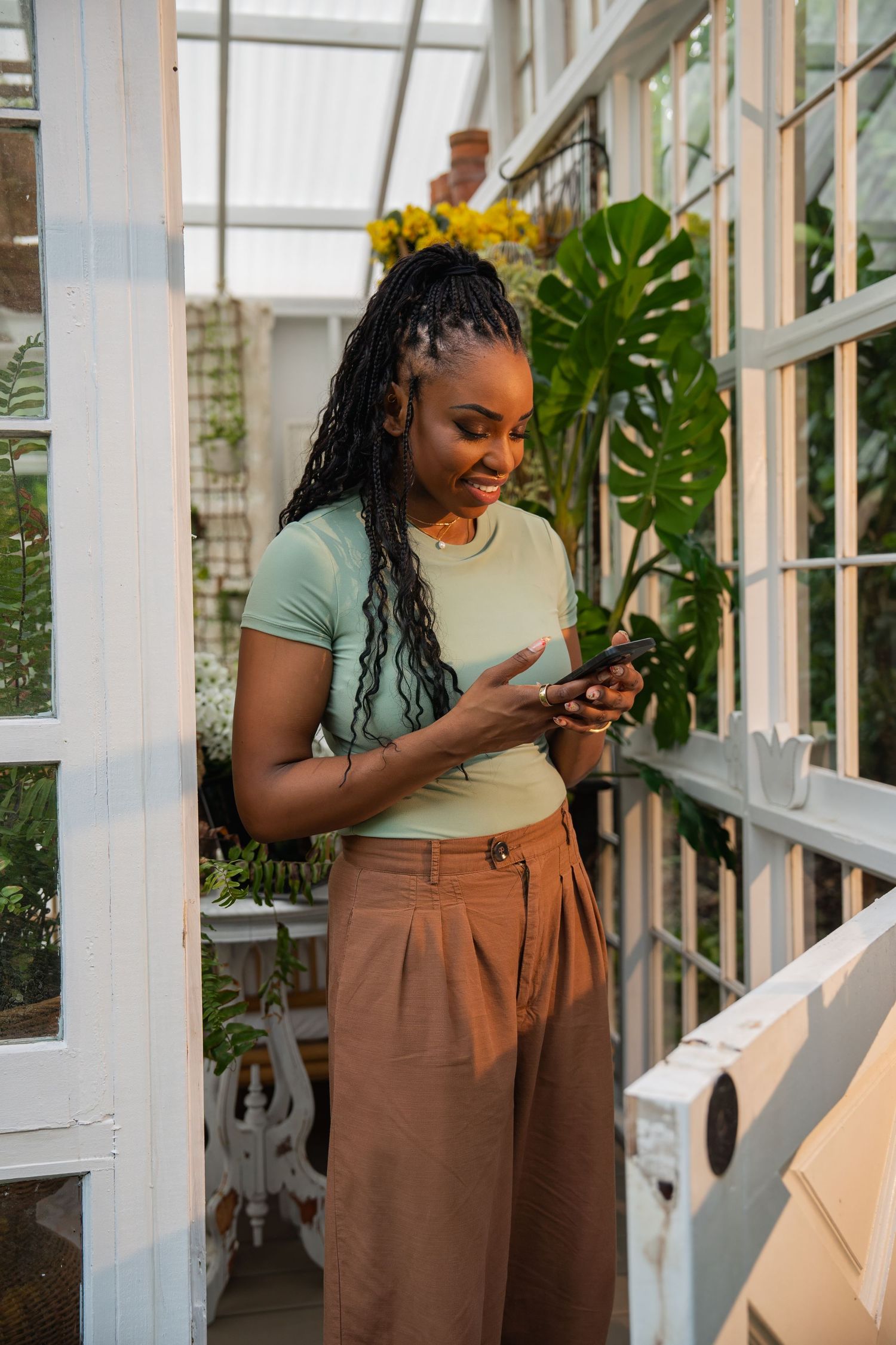 South Florida lifestyle branding portrait of woman working on her phone in greenhouse studio