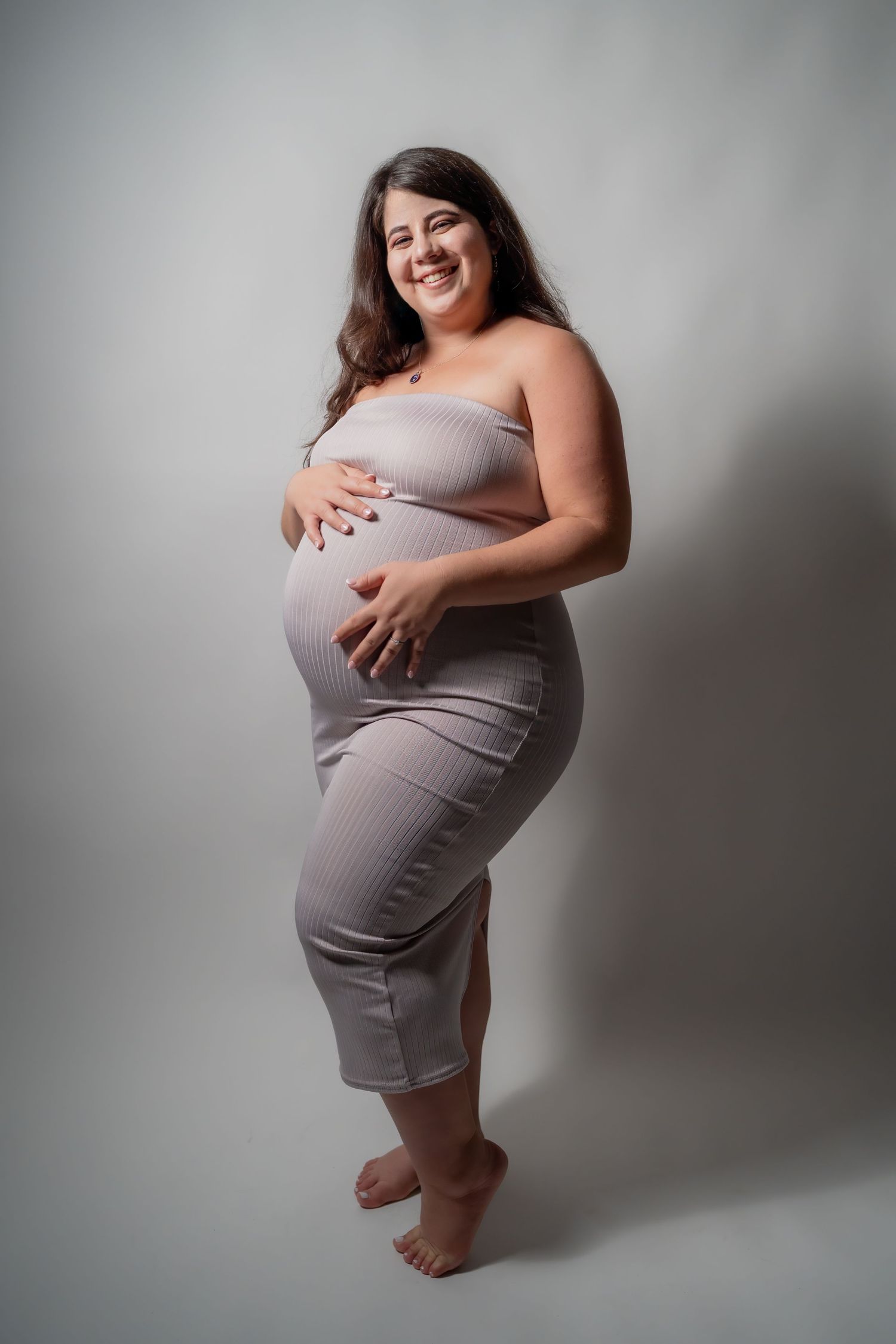 Studio maternity portrait of pregnant woman in neutral dress against soft backdrop