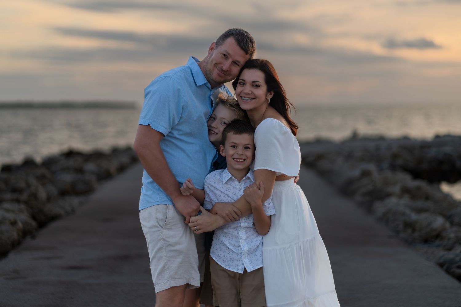 Family beach photos in South Florida by photographer, sunset portrait session with parents and child on jetty