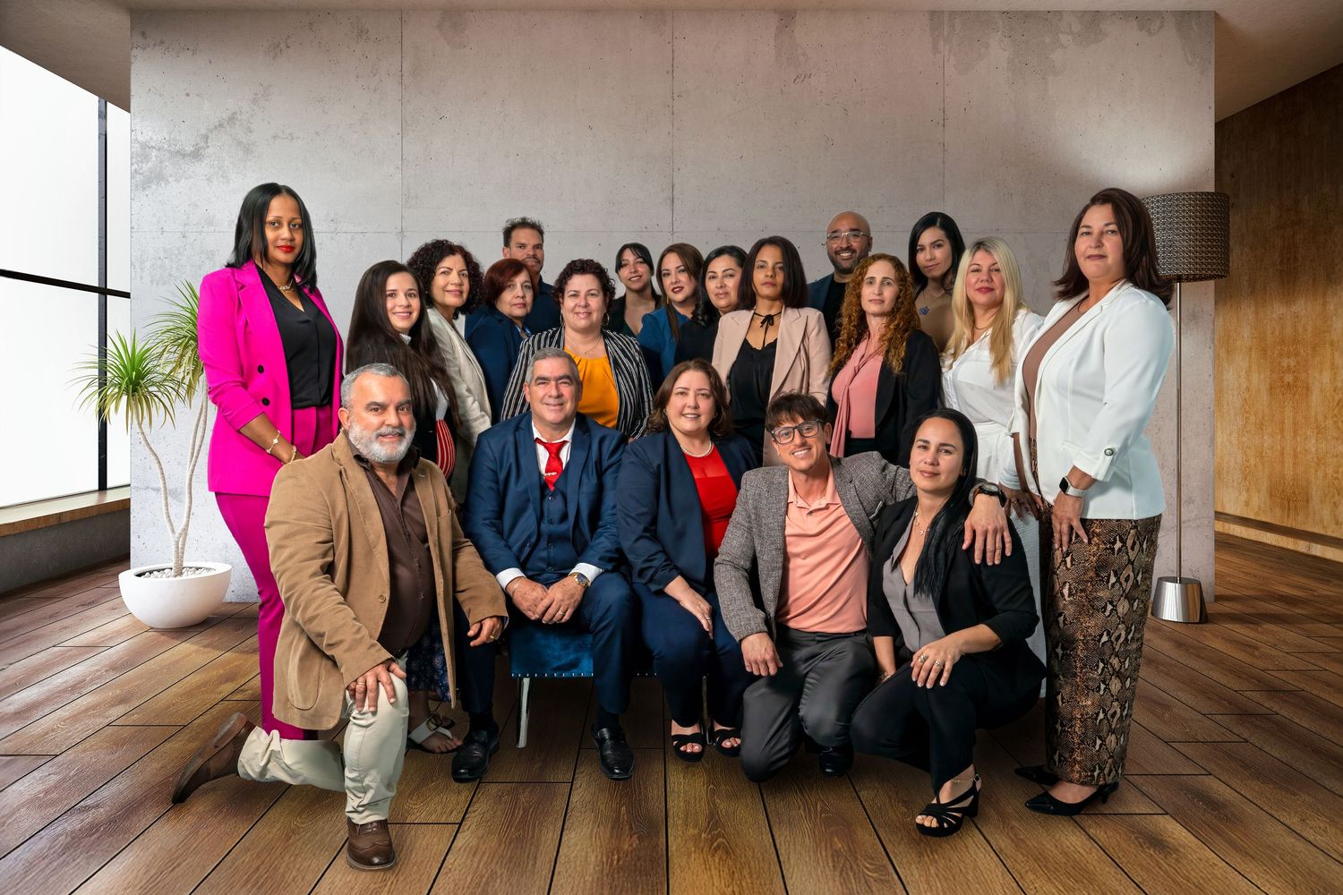 Large group team portrait taken in a stylish office space with floor-to-ceiling windows.
