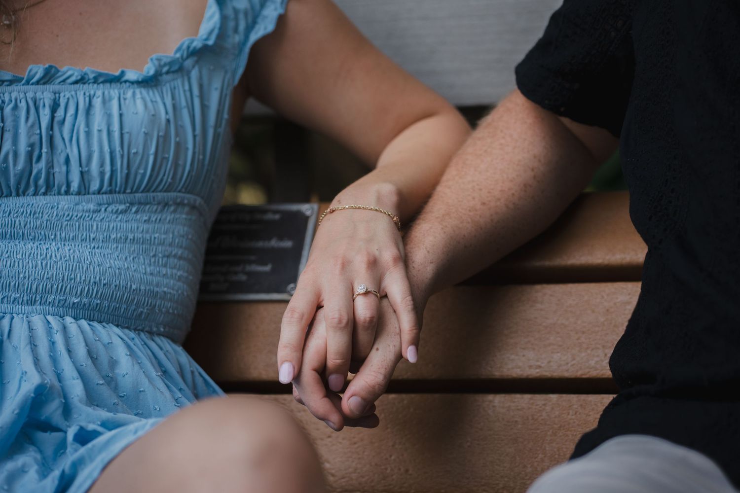 Close-up engagement photography of couple holding hands on park bench in South Florida