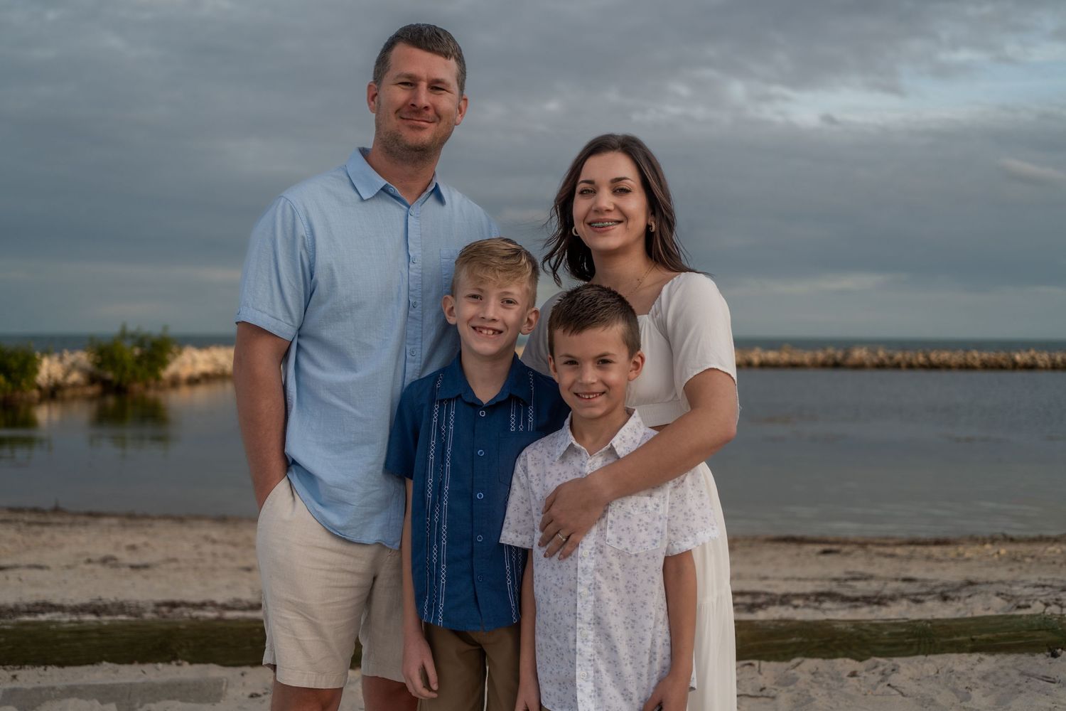 Cozy family portrait at Harry Harris Park, Tavernier, FL – parents and kids sharing a warm moment by the ocean before sunset.