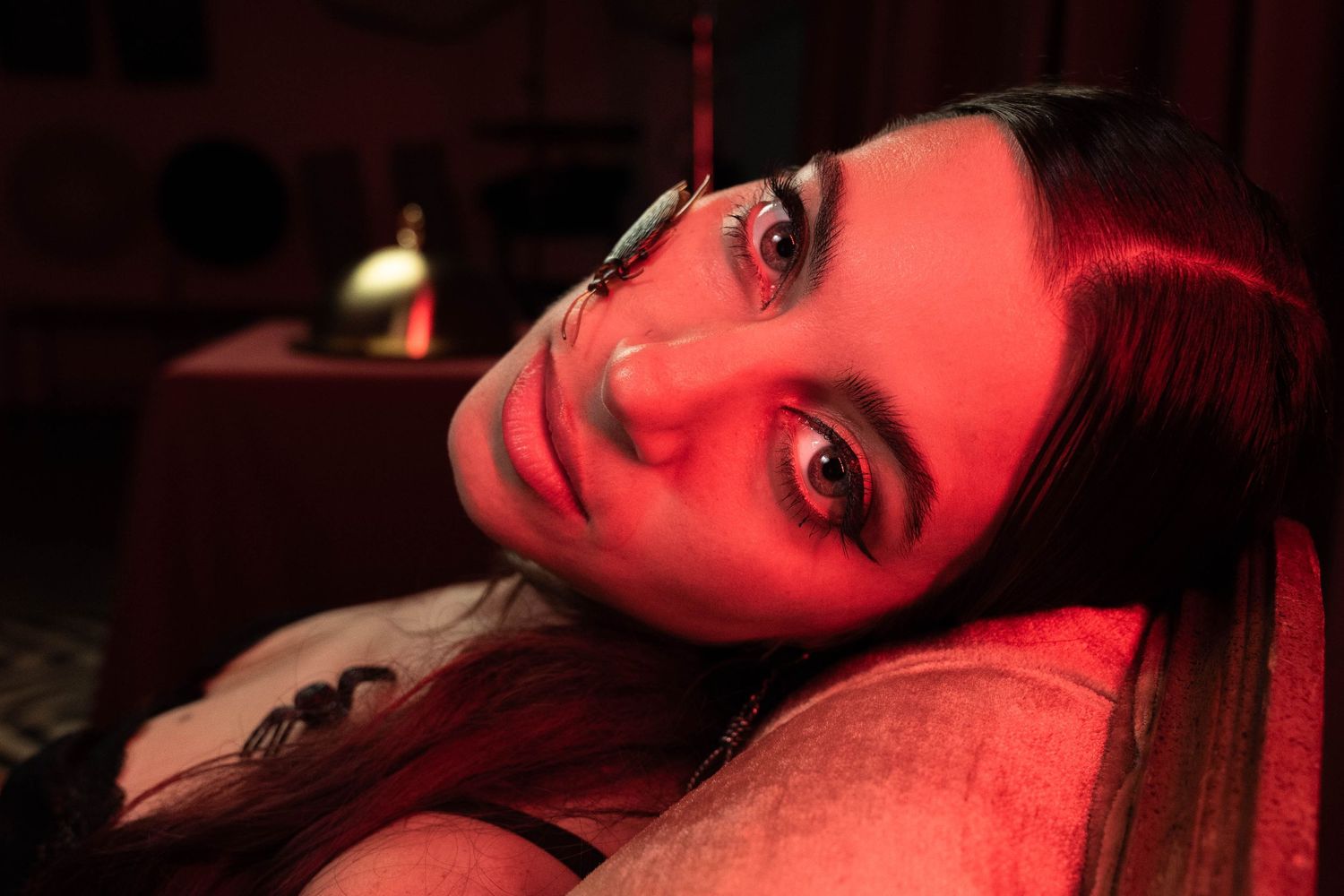 Dramatic low-light portrait in Boca Raton, FL – woman gazing at the camera in a sultry red-lit setting.