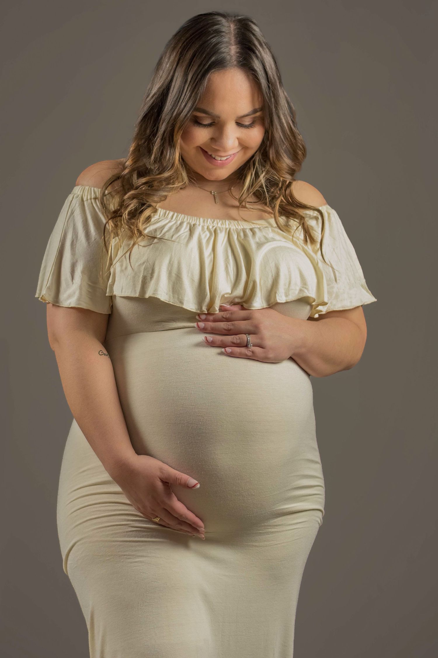 Elegant studio maternity portrait with soft lighting, capturing a mother’s anticipation and love.