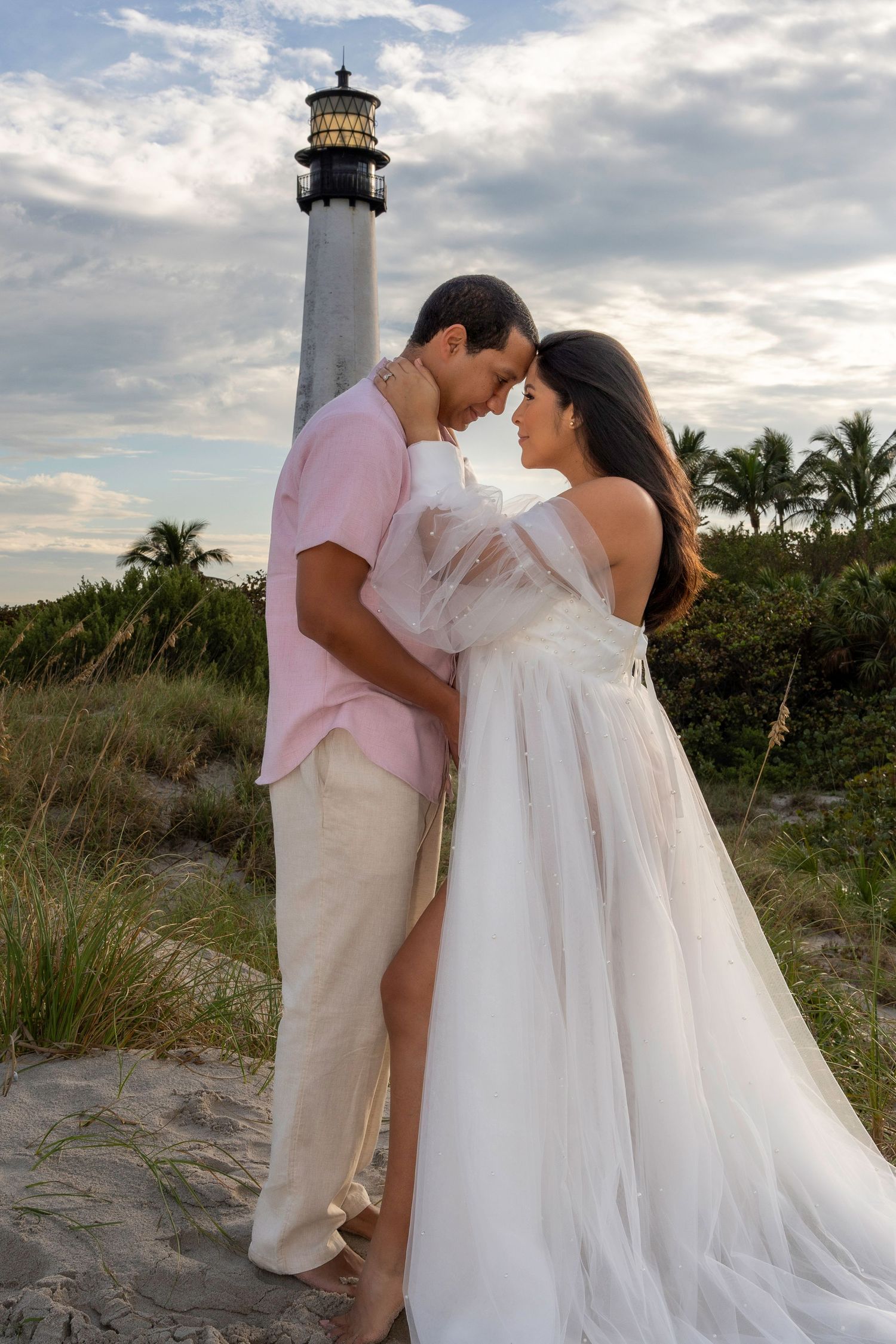 Timeless maternity portrait at Cape Florida Lighthouse, with the couple sharing a sweet moment along the coastal path.
