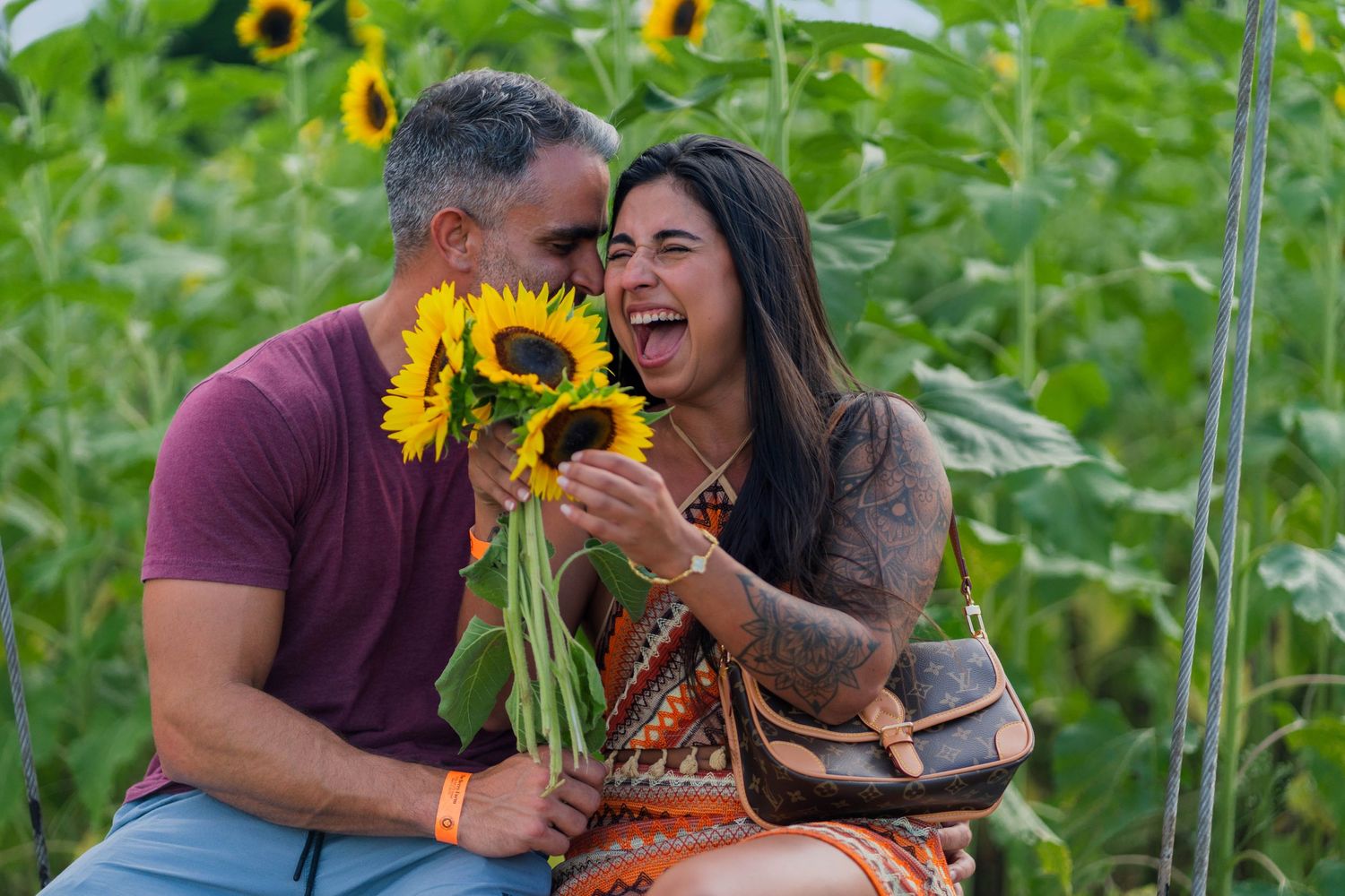 Candid couple photography at Berry Farms, capturing genuine laughter and romance among blooming sunflowers.