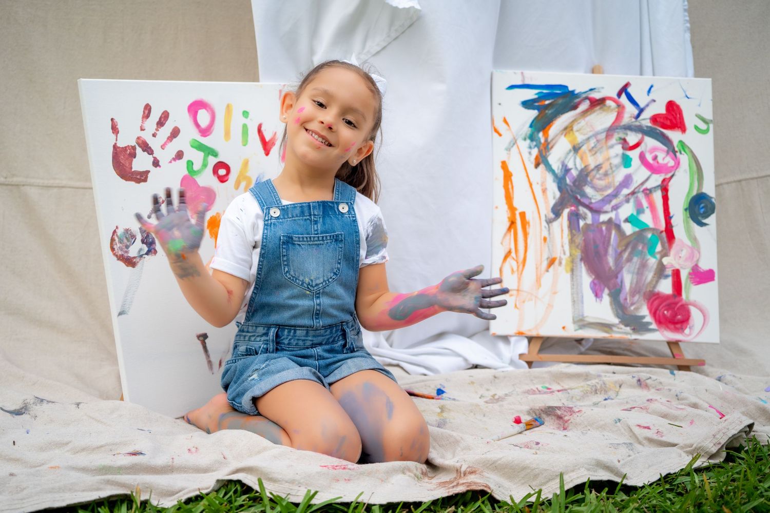 Girl holding up a painted hand and smiling during a Mommy & Me mini session in South Florida.