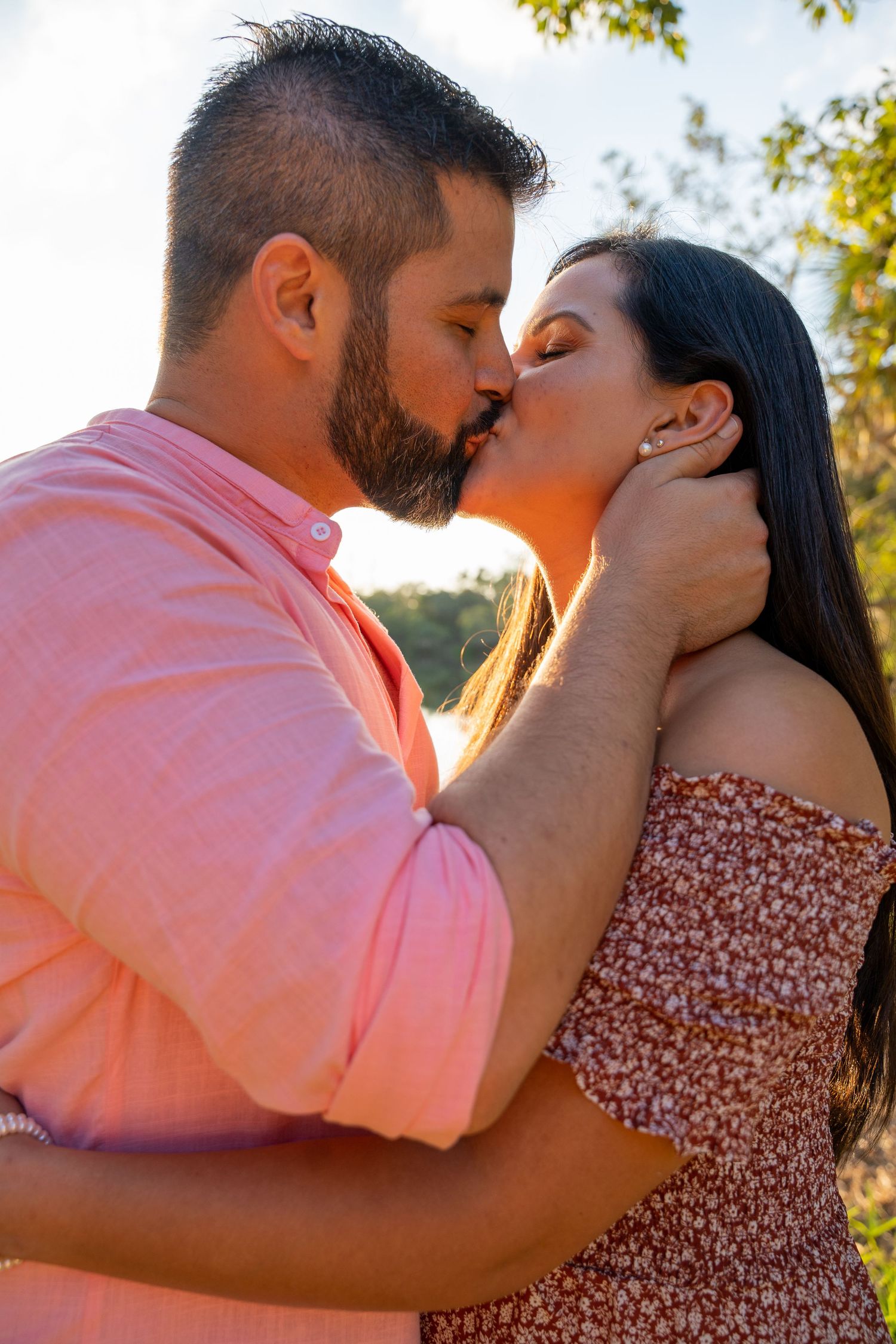 Intimate moment between an expecting couple sharing a kiss during a South Florida gender reveal celebration.
