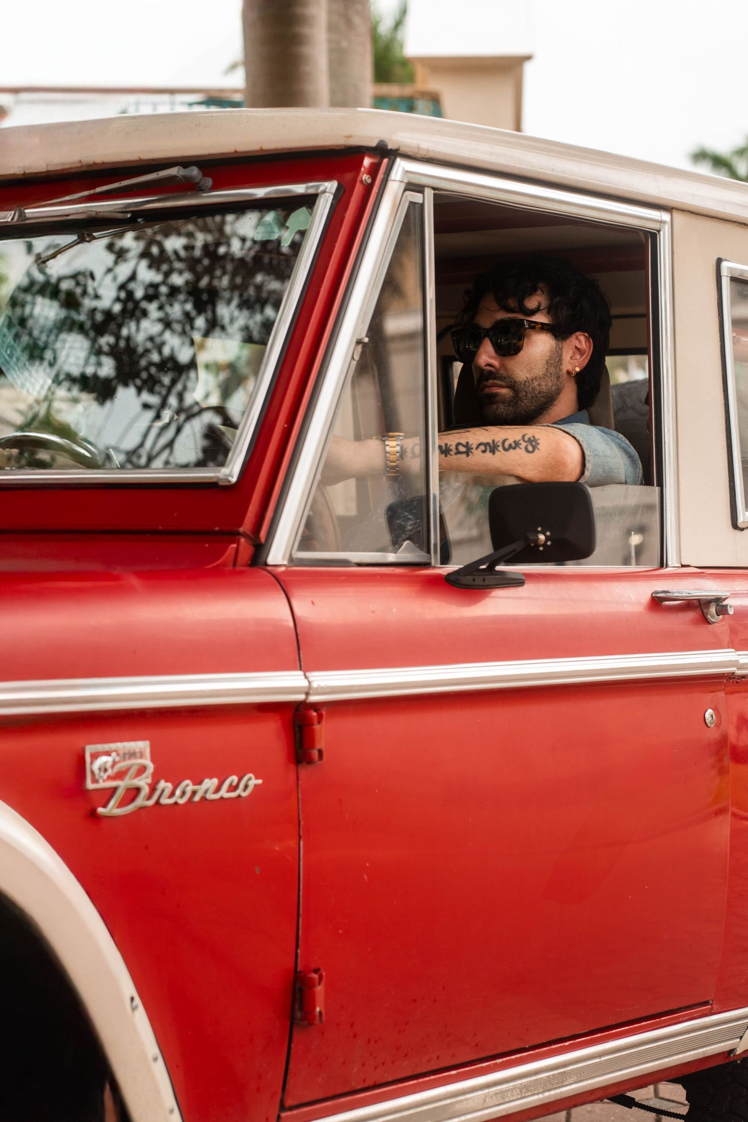 Editorial car photography in Palm Beach, FL – stylish man behind the wheel of a vintage red Bronco, creating a nostalgic feel.