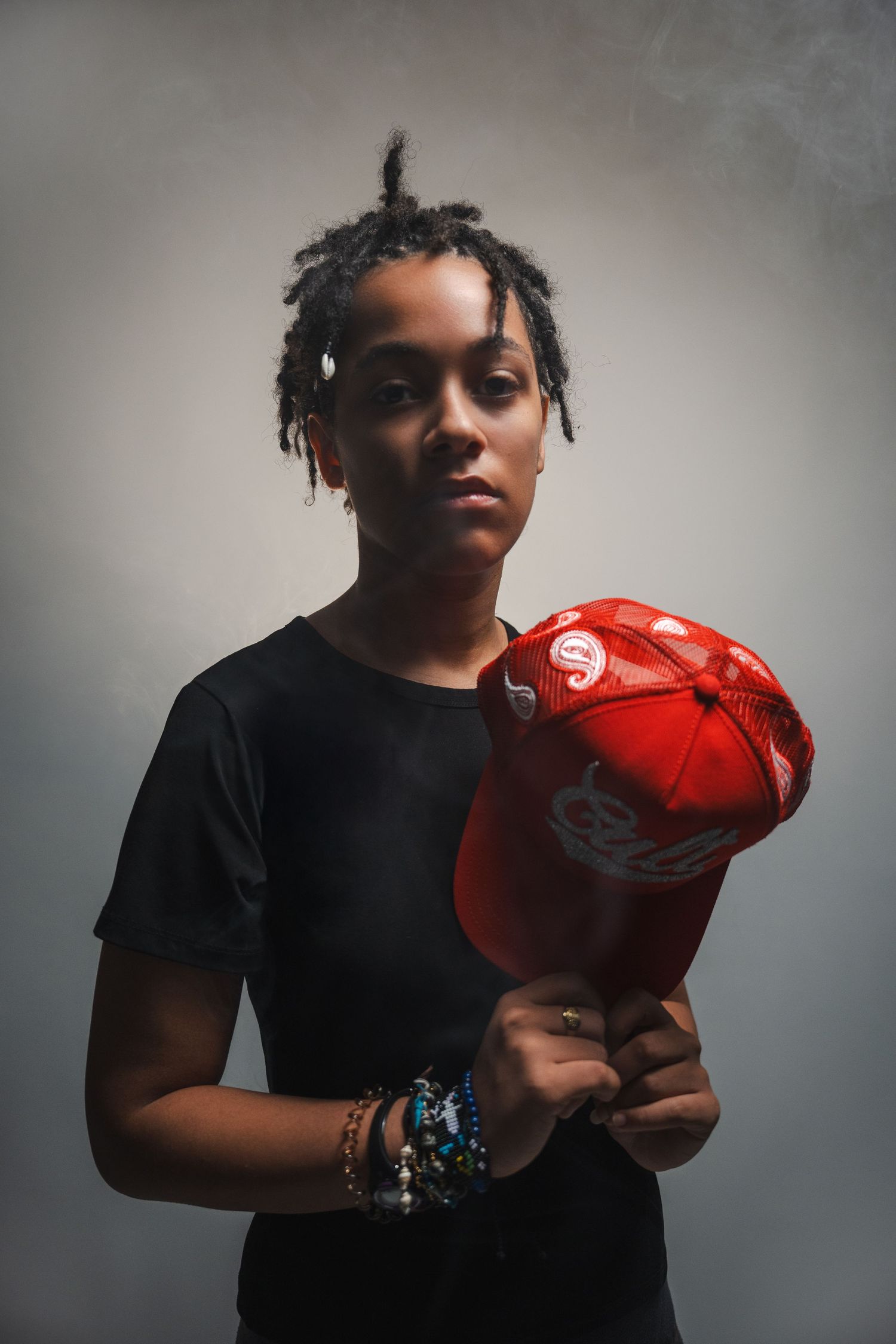 Studio senior portraits in South Florida by photographer, moody lighting with subject holding red prop for artistic concept