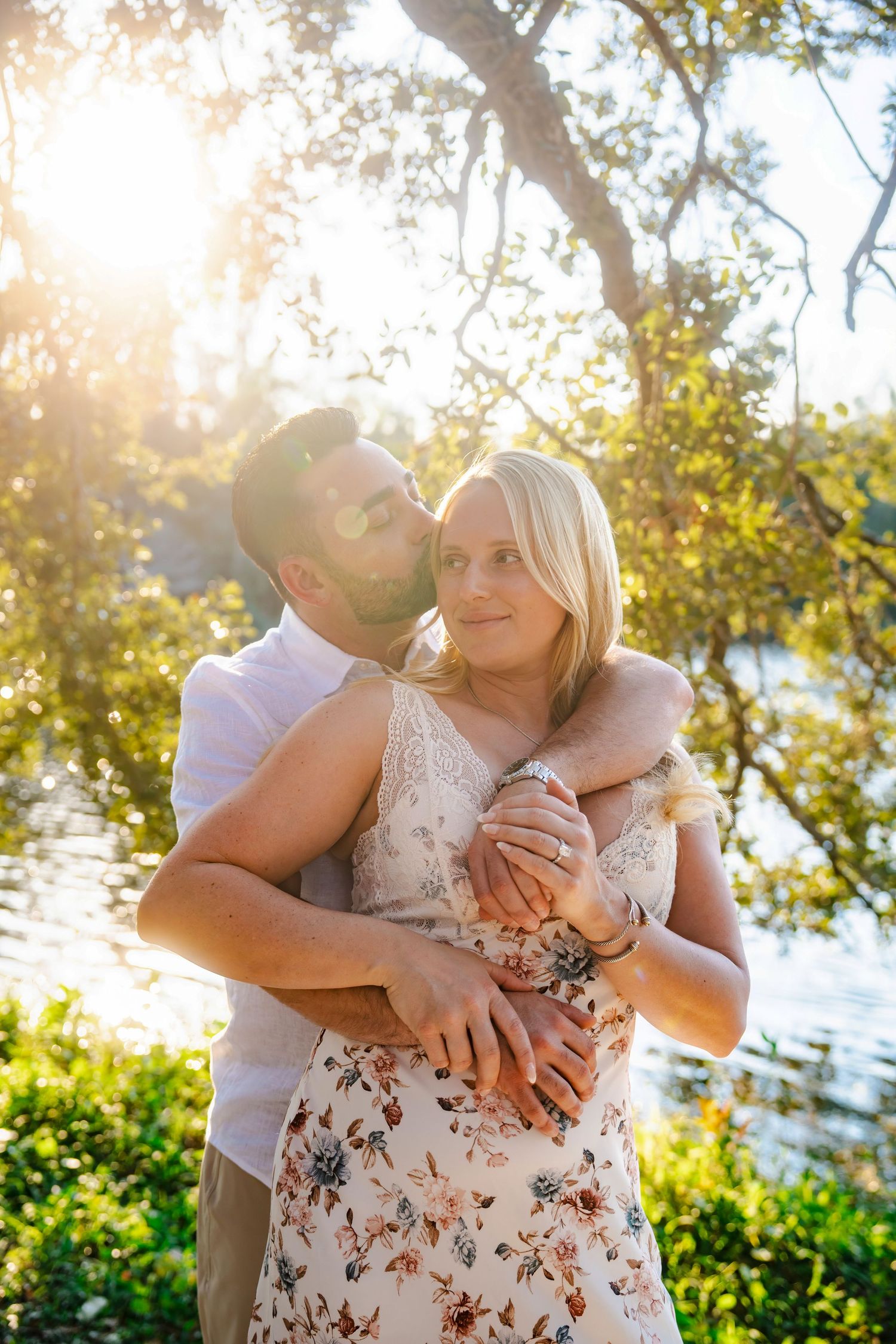 Romantic engagement portrait created through a guided session with couple embracing in soft golden light at Tree Tops Park