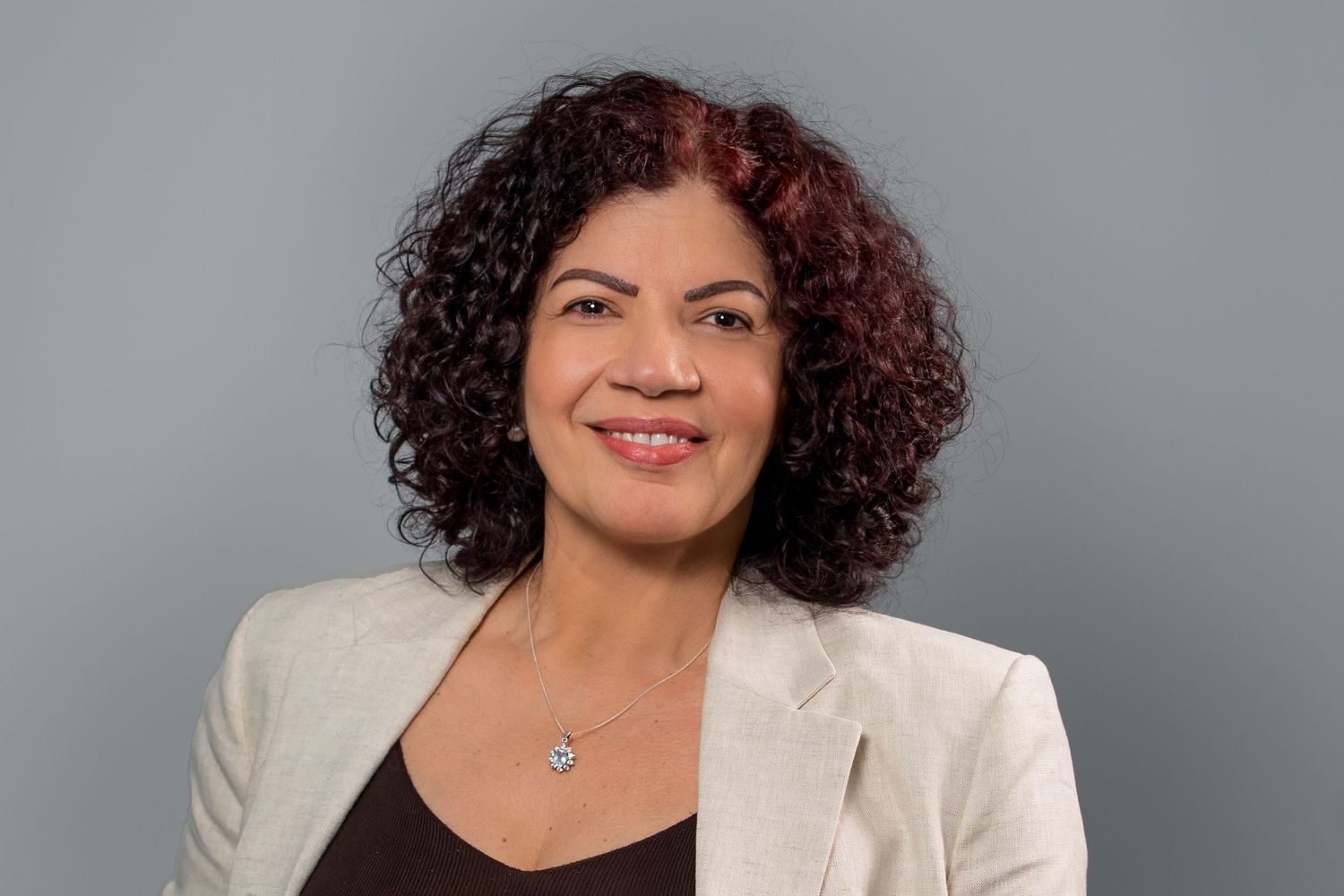 Woman with curly hair smiling during studio professional headshot session