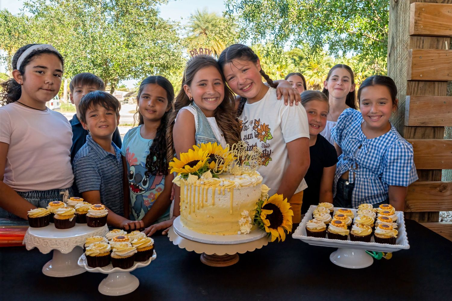 riends surrounding cake table at Berry Farms, sunflower-themed birthday in Miami.