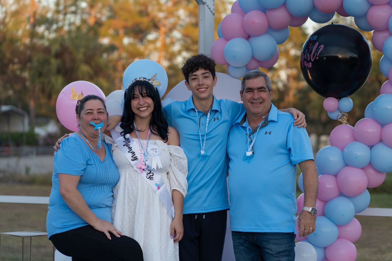 Family portrait with expecting parents and relatives smiling together at a South Florida gender reveal event.