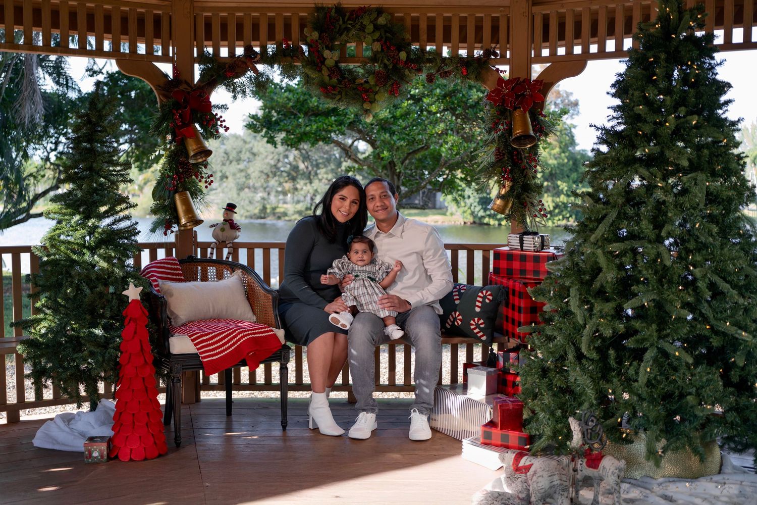 Cozy holiday mini session in Miami, FL – family sitting in a festive Christmas gazebo decorated with garlands and lights.