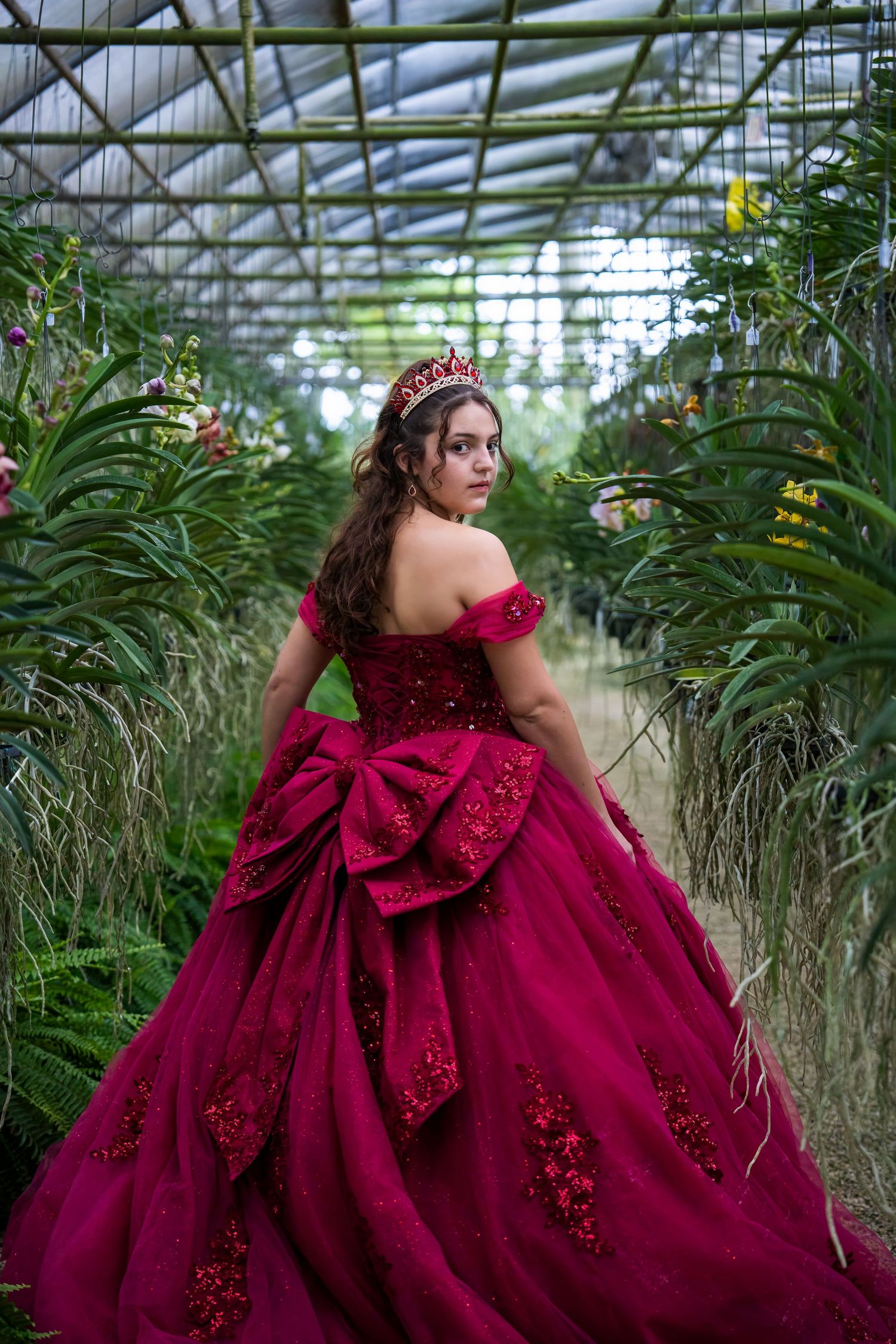 Quinceañera portrait at RF Orchids featuring a young woman in a red gown, captured with an editorial style in South Florida.