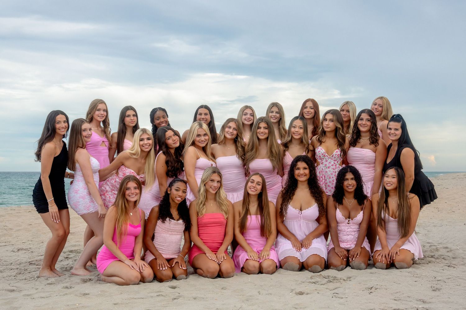 Large cheer squad group portrait on the beach, captured during a South Florida session with soft coastal light.